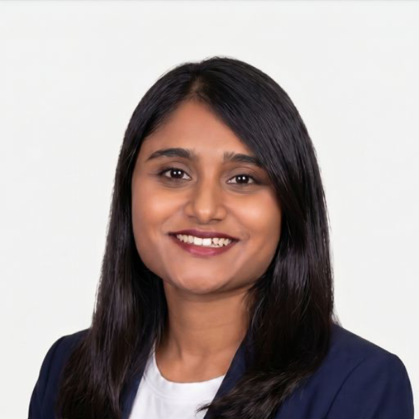 Professional woman with shoulder-length dark hair, wearing a navy blazer and white shirt, smiling against a plain white background.