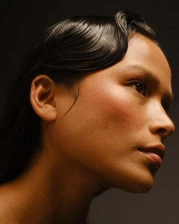 Close-up profile of a woman with dark hair and smooth skin. Los Angeles premiere hair and makeup artist, Amber Rose.