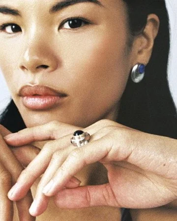 Close-up beauty shot pairing a delicate drop earring with a statement gemstone ring, jewelry-focused editorial makeup by Los Angeles artist Amber Rose.