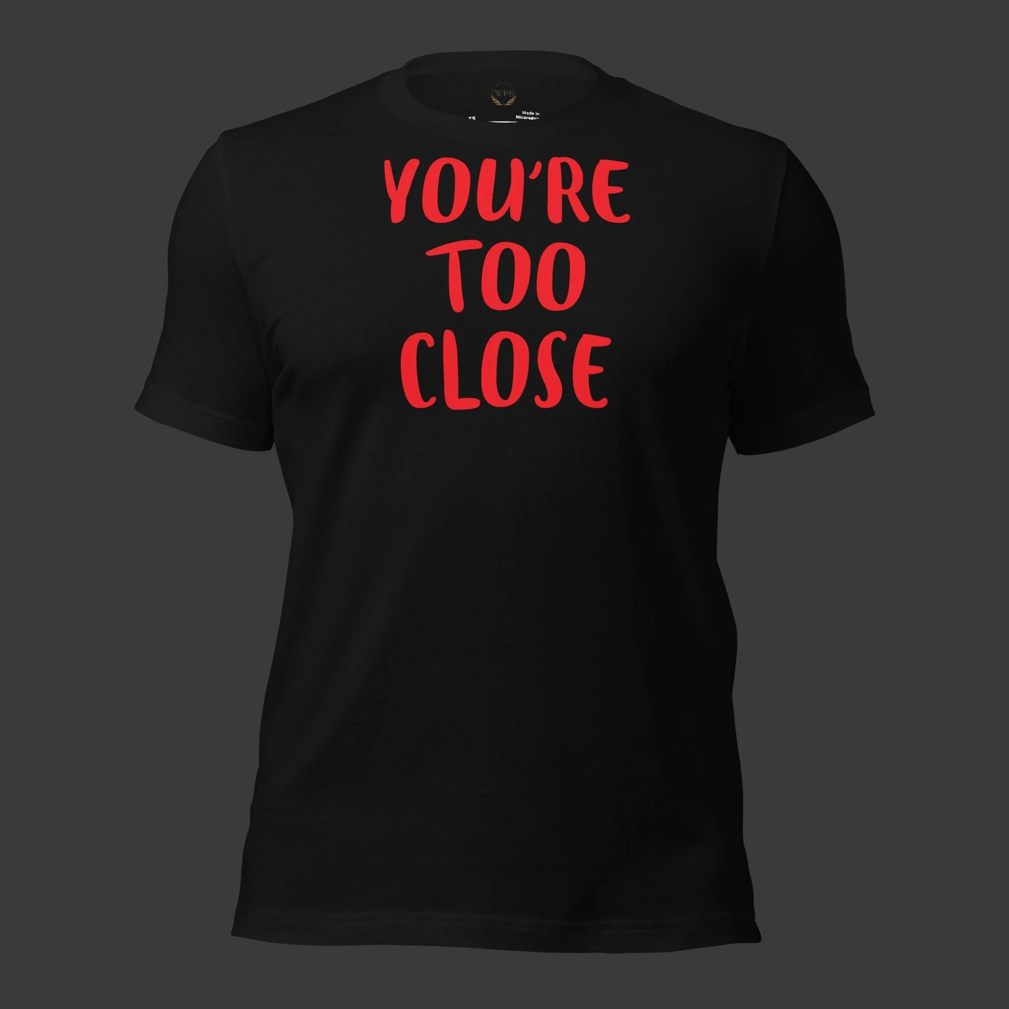 Unisex graphic t-shirt from WPB Emporium featuring the “You’re Too Close” design displayed against a dark charcoal background.