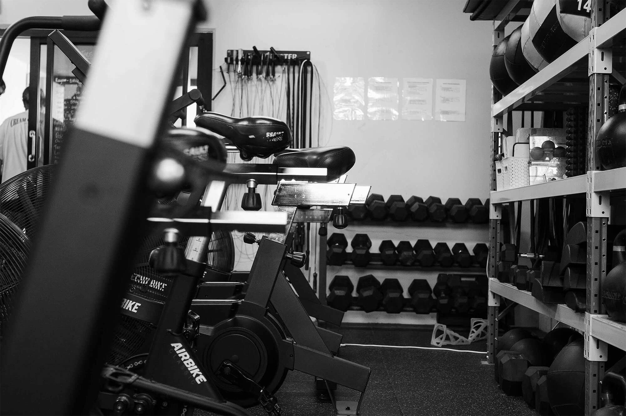 A photo of the bike ergs, echo bikes and assault bikes in the foreground, and kettlebell, dumbbell, wall ball and kipping rope shelving in the background at CrossFit TARIS in Brisbane.