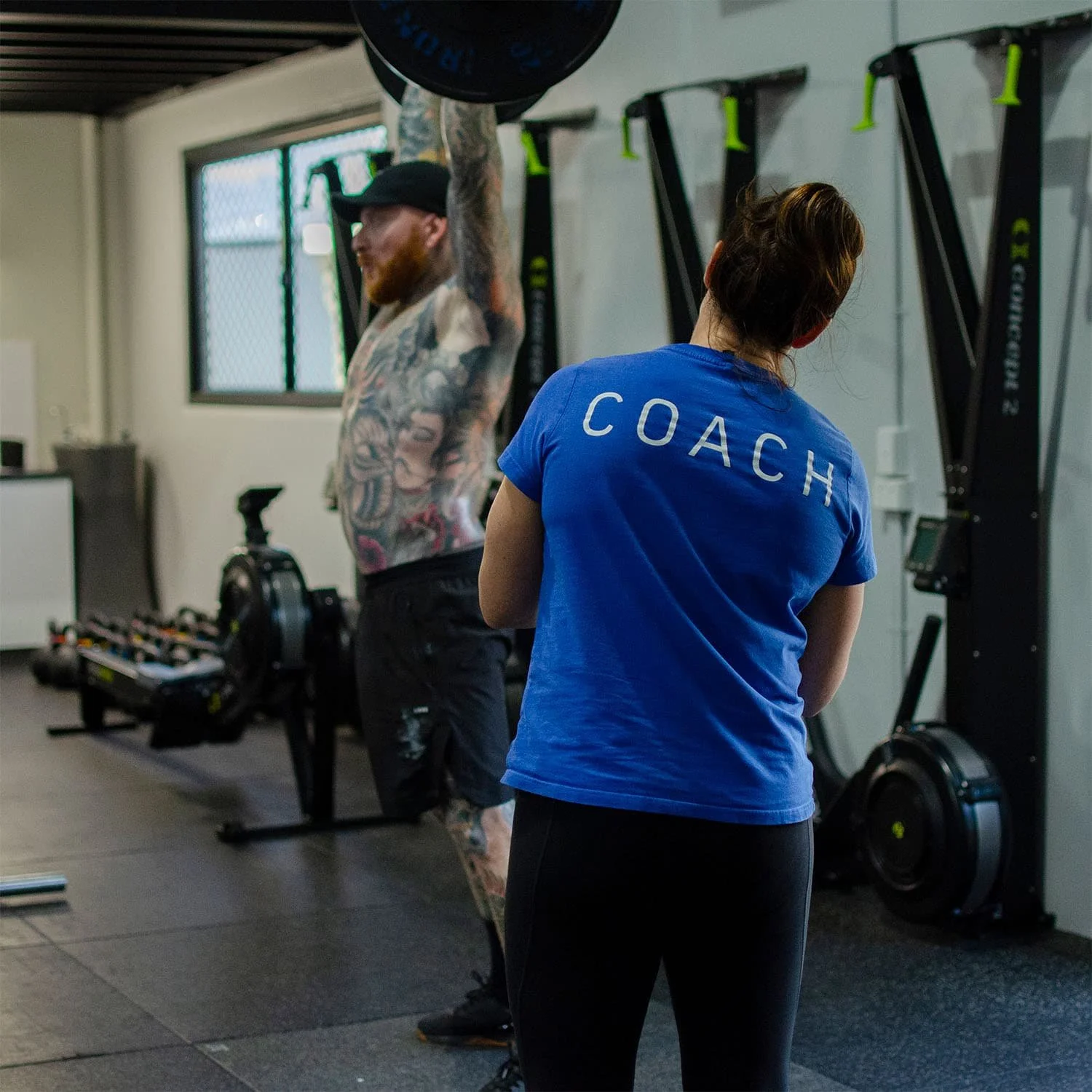 Coach Lisa watching the form of a member performing an overhead barbell lift at CrossFit TARIS.