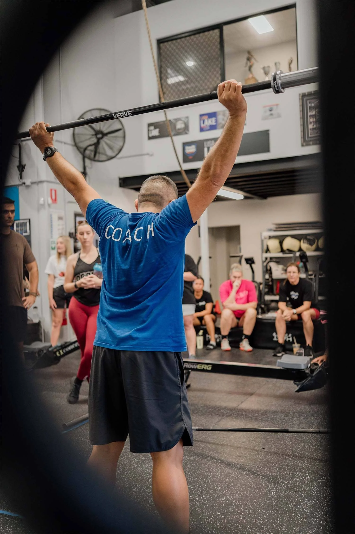 Coach Rigo demonstrating a snatch overhead position during a member briefing at CrossFit TARIS in Logan.