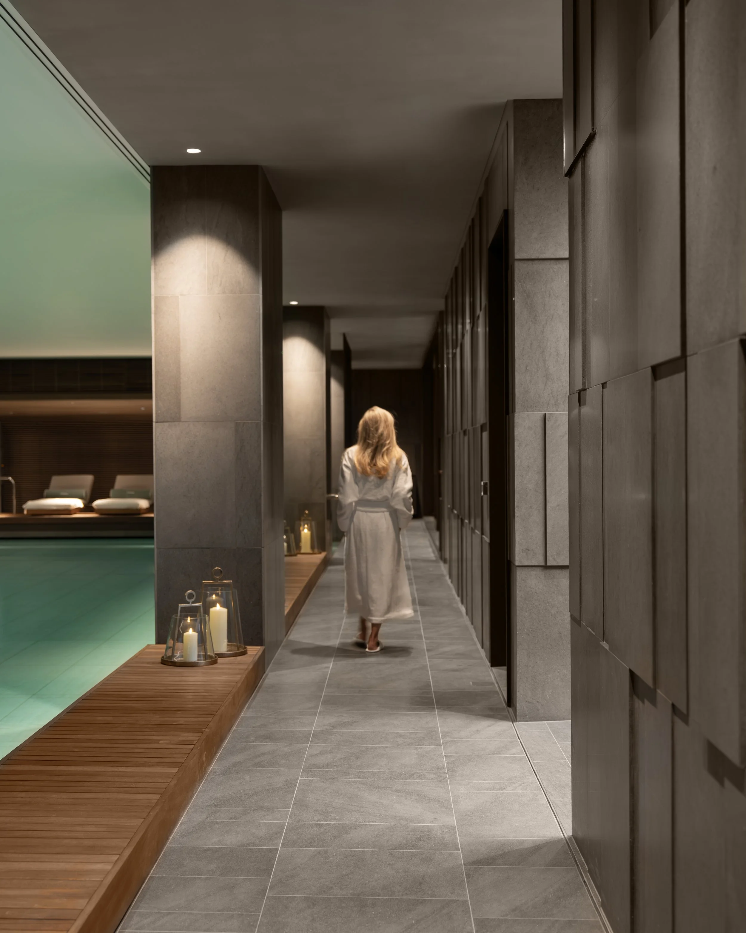 Resident in a robe walking beside the candlelit swimming pool in the Holland Park Gate health club and spa, Kensington, London