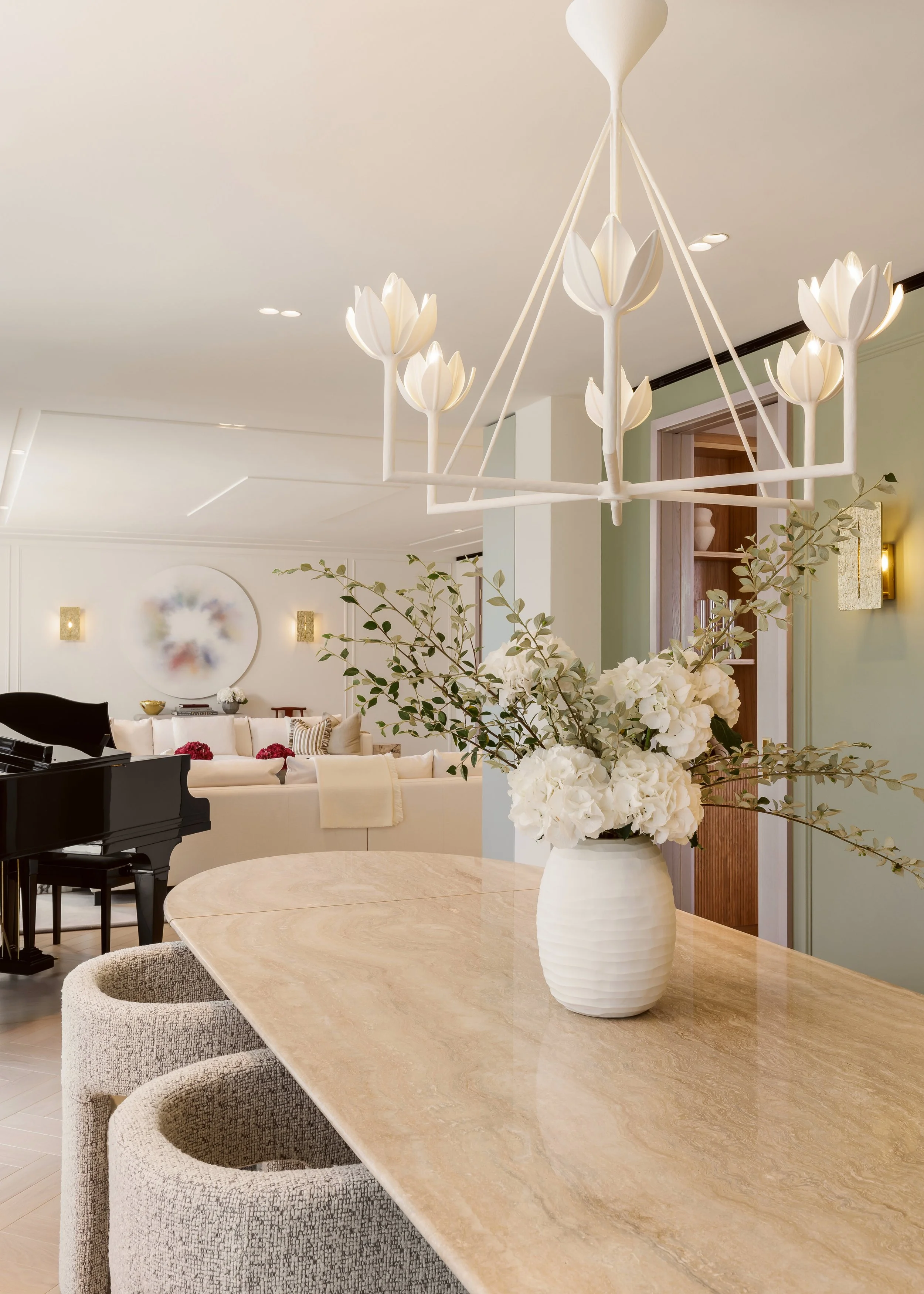 Travertine dining table beneath a sculptural flower chandelier in a four-bedroom apartment at Holland Park Gate, London