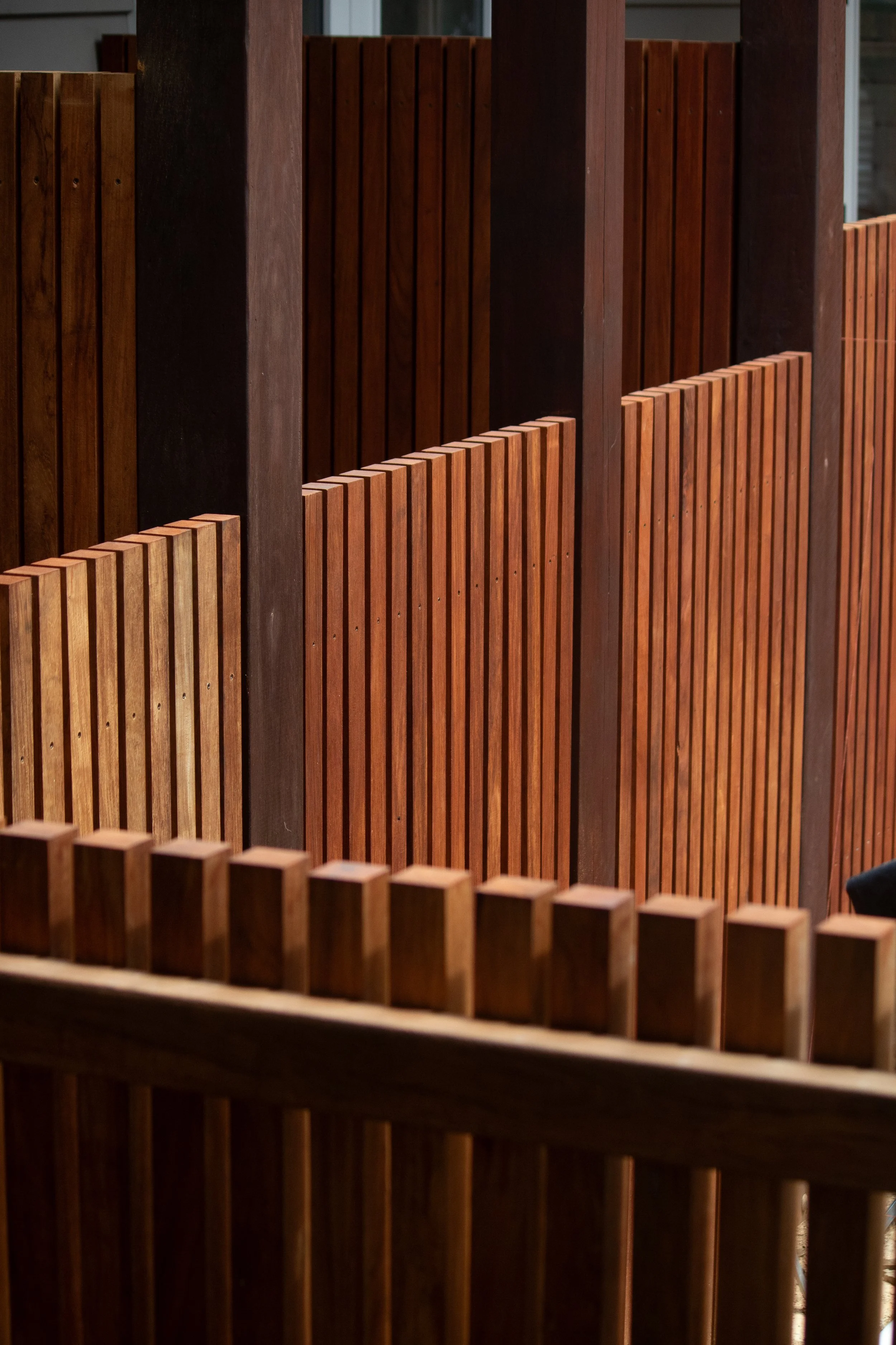 Close-up view of a decorative wooden fence with vertical slats in varying shades of brown.