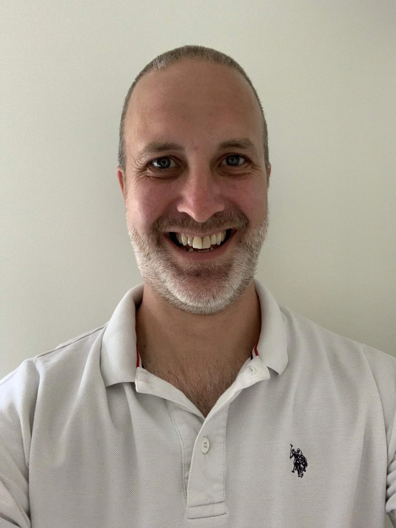 Smiling man in white polo shirt