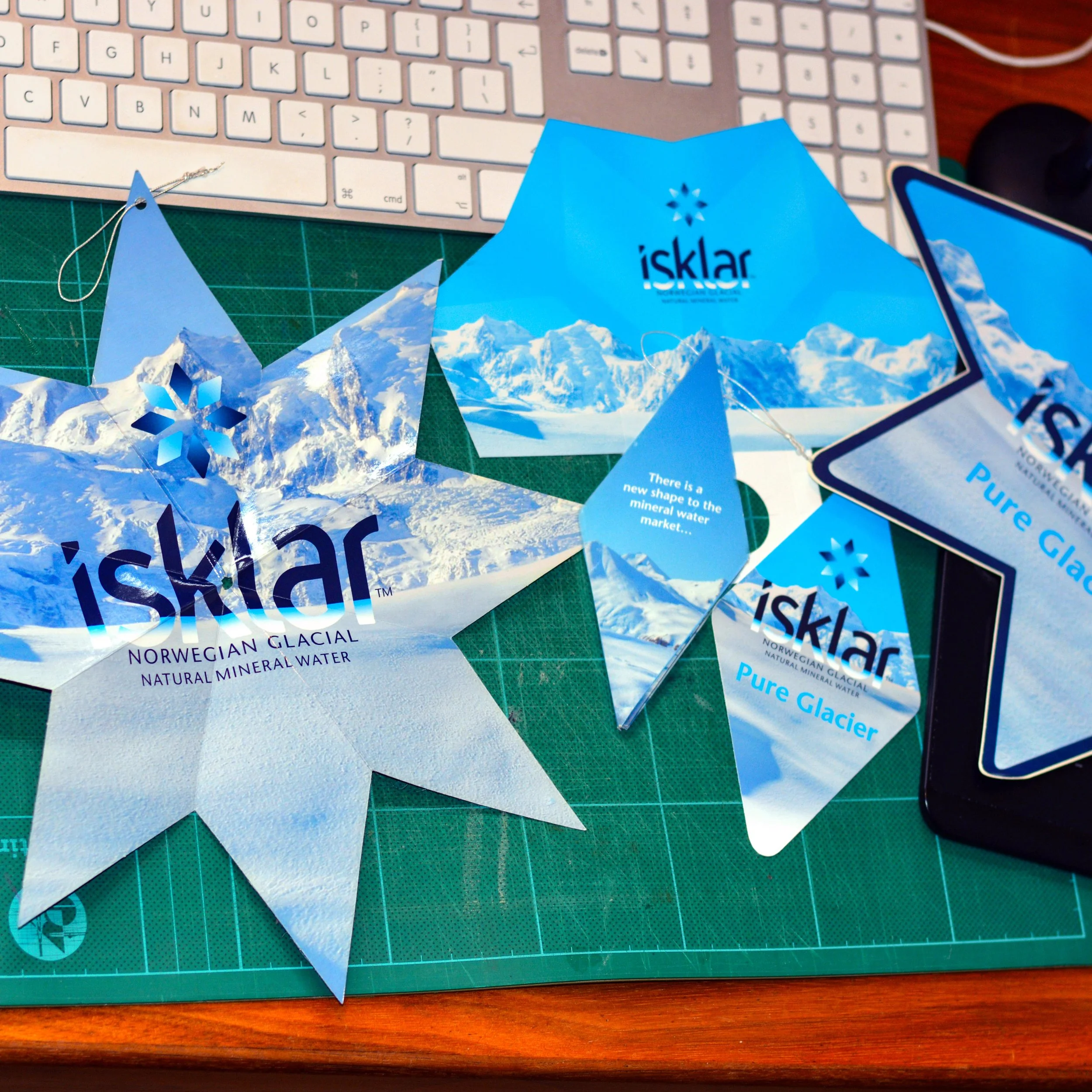 Isklar Norwegian Mineral Water product launch materials sitting on my desk. The neck tag is shown opened up and folded away along with a shelf wobbler, fridge sticker and bottle collar.