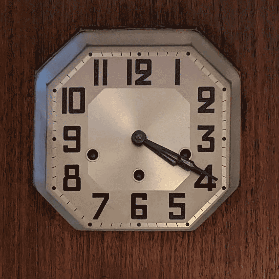 Octagonal clock face with art deco numerals set into a wooden case.