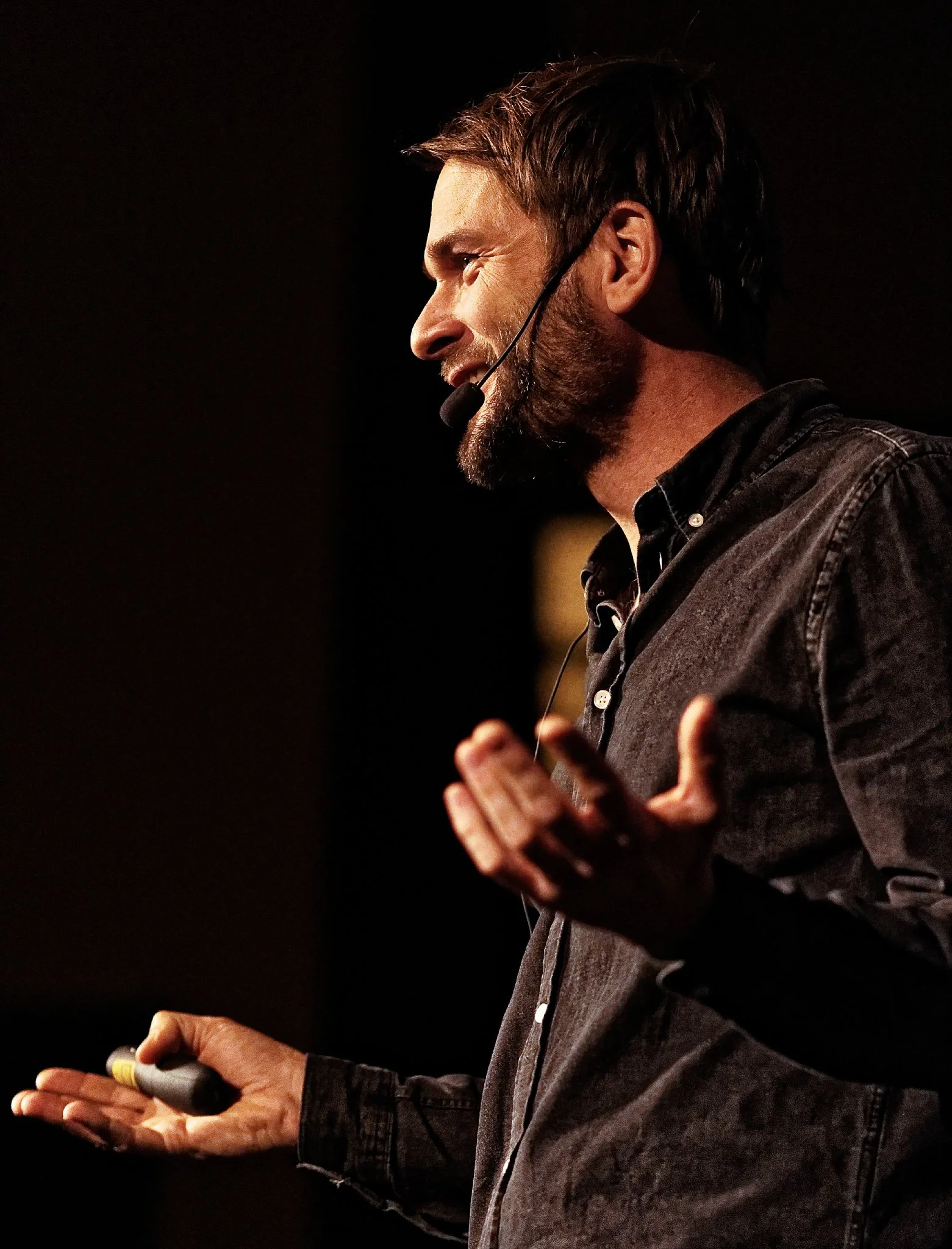 Man speaking into a microphone and using hand gestures.