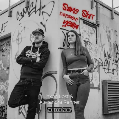 Schwarz-Weiß-Foto eines Mannes und einer Frau, die gegen eine graffiti-beschmierte Wand in einer urbanen Umgebung lehnen. Text auf der Wand: "Same Shit, Different Year". Untertitel: "Jaxon Lost & Alexandra Renner" und ein Logo mit dem Wort "SO LEBENDIG".