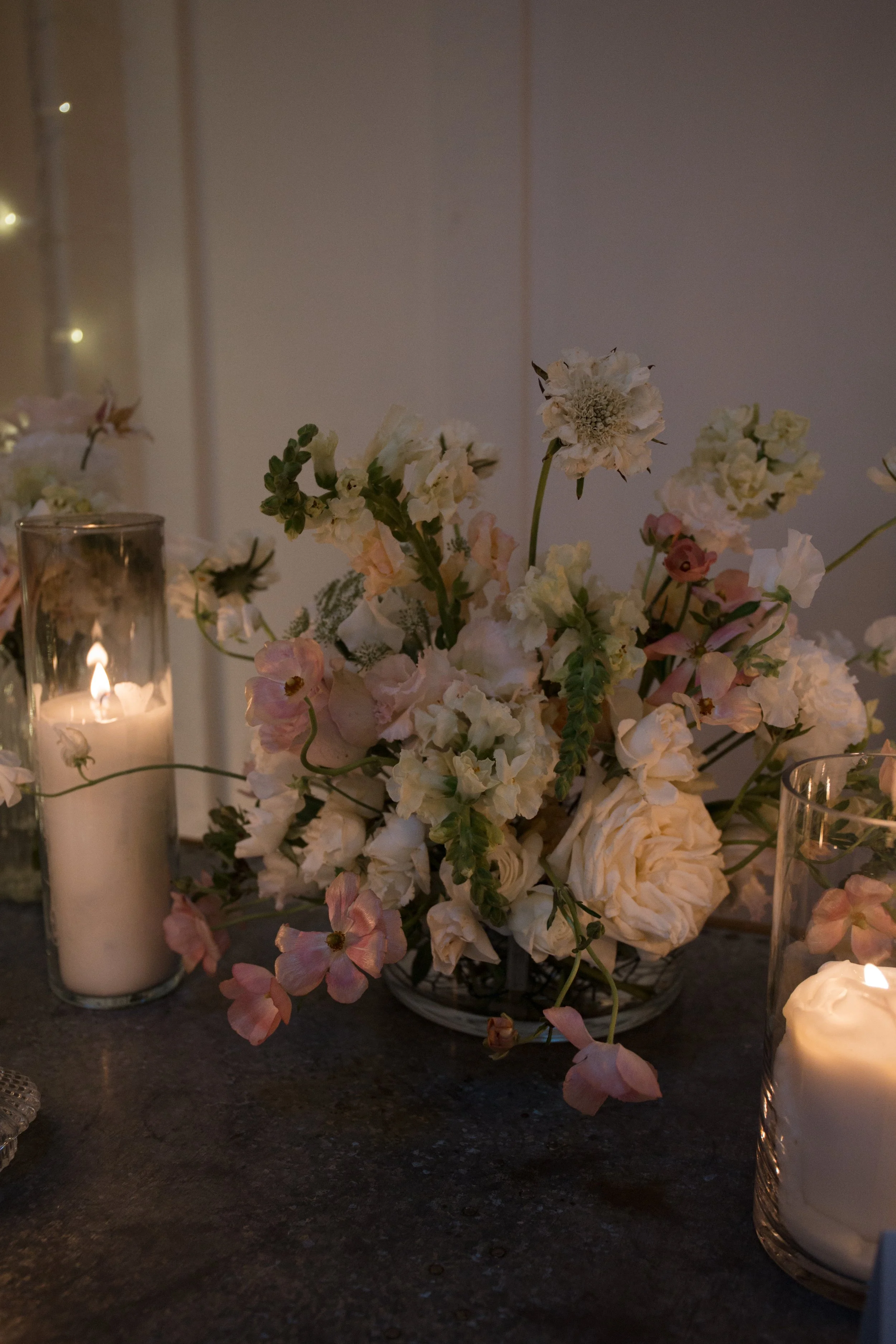 Candle lit wedding table bowl with garden roses, butterfly ranunculus and Ammi at Millbridge Court