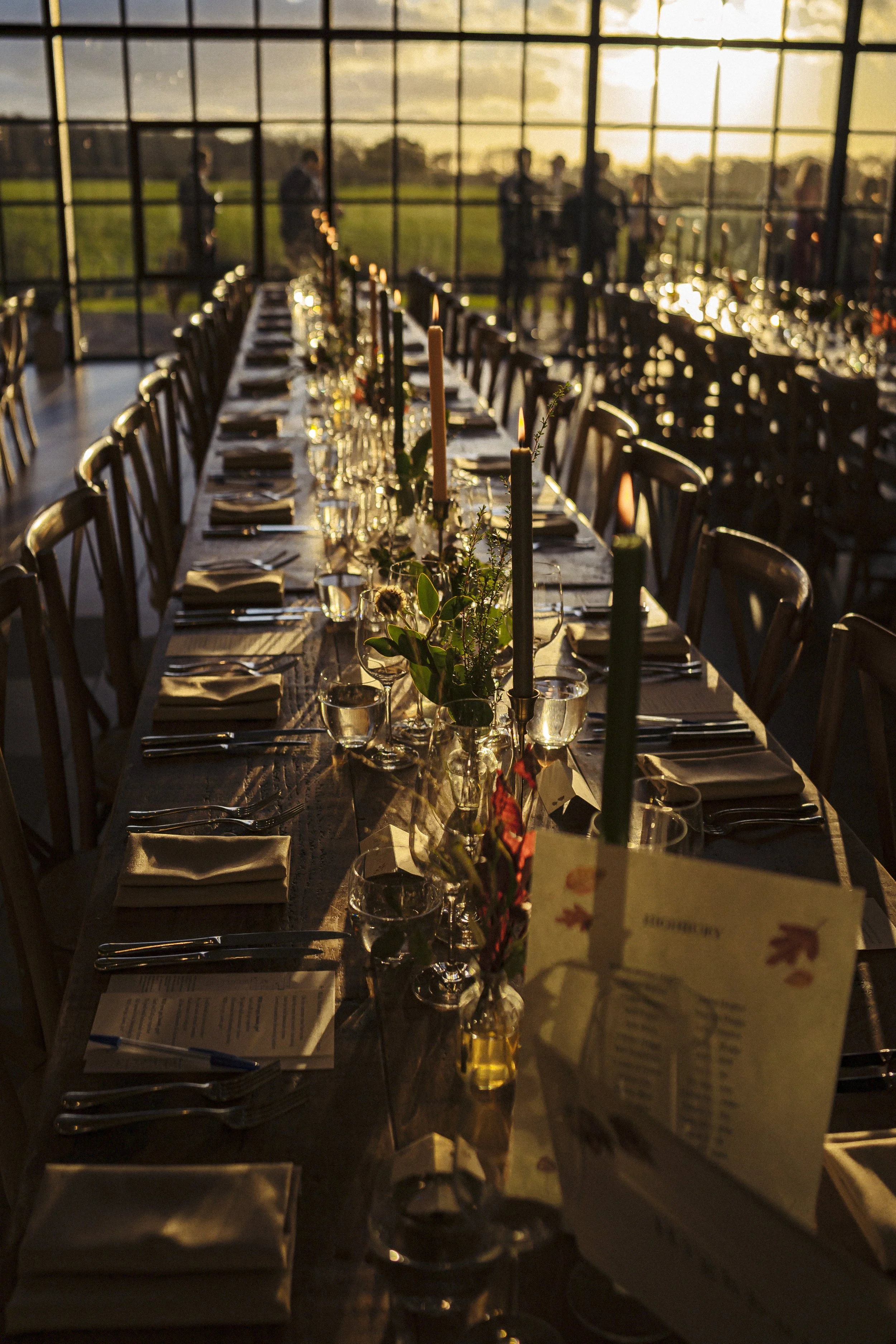 Long banquet tables filled with foliage bud vases and candlelight amongst the surrey hills
