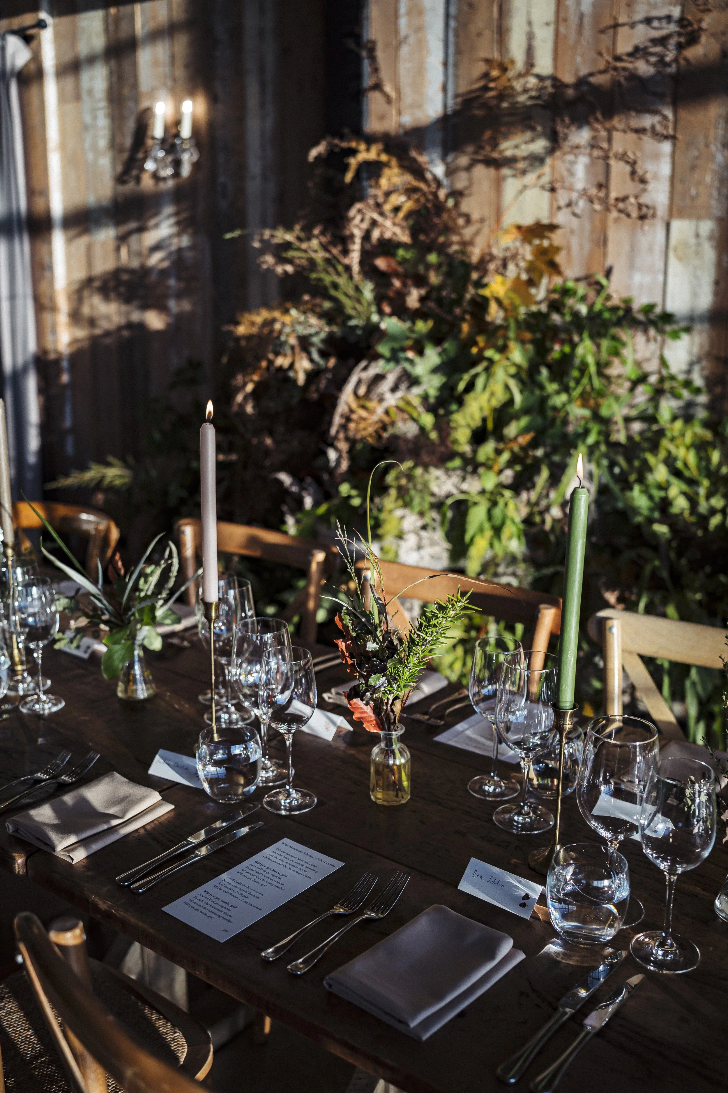 Long banquet top table filled with foliage bud vases and candlelight amongst the surrey hills