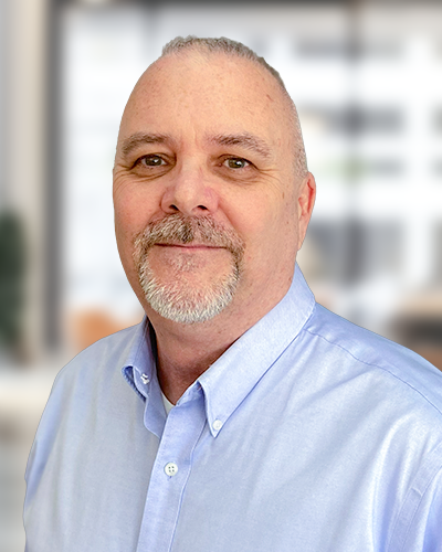 portrait of middle age man in light blue button up with shallow depth of field blurred office background