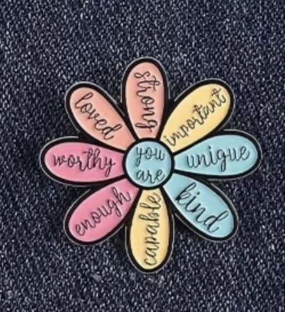 Colourful flower-shaped enamel pin badge with positive words like "loved," "worthy," "enough," "caring," "you are," "strong," "important," "unique," and "kind," mental health (Anchored Thoughts)