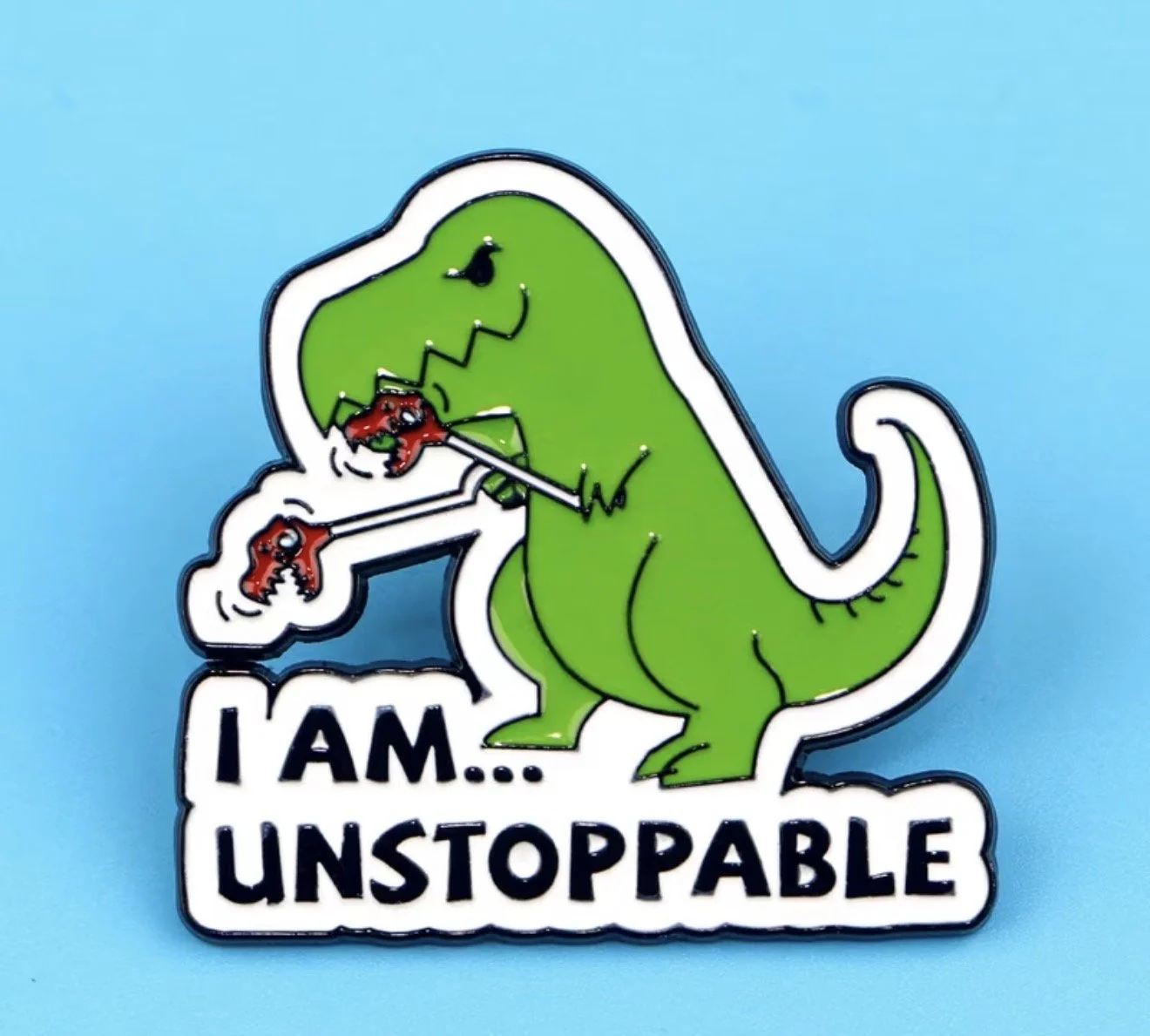 A  pin badge featuring a green dinosaur, with the text "I AM... UNSTOPPABLE" at the bottom. Mental Health (Anchored Thoughts)