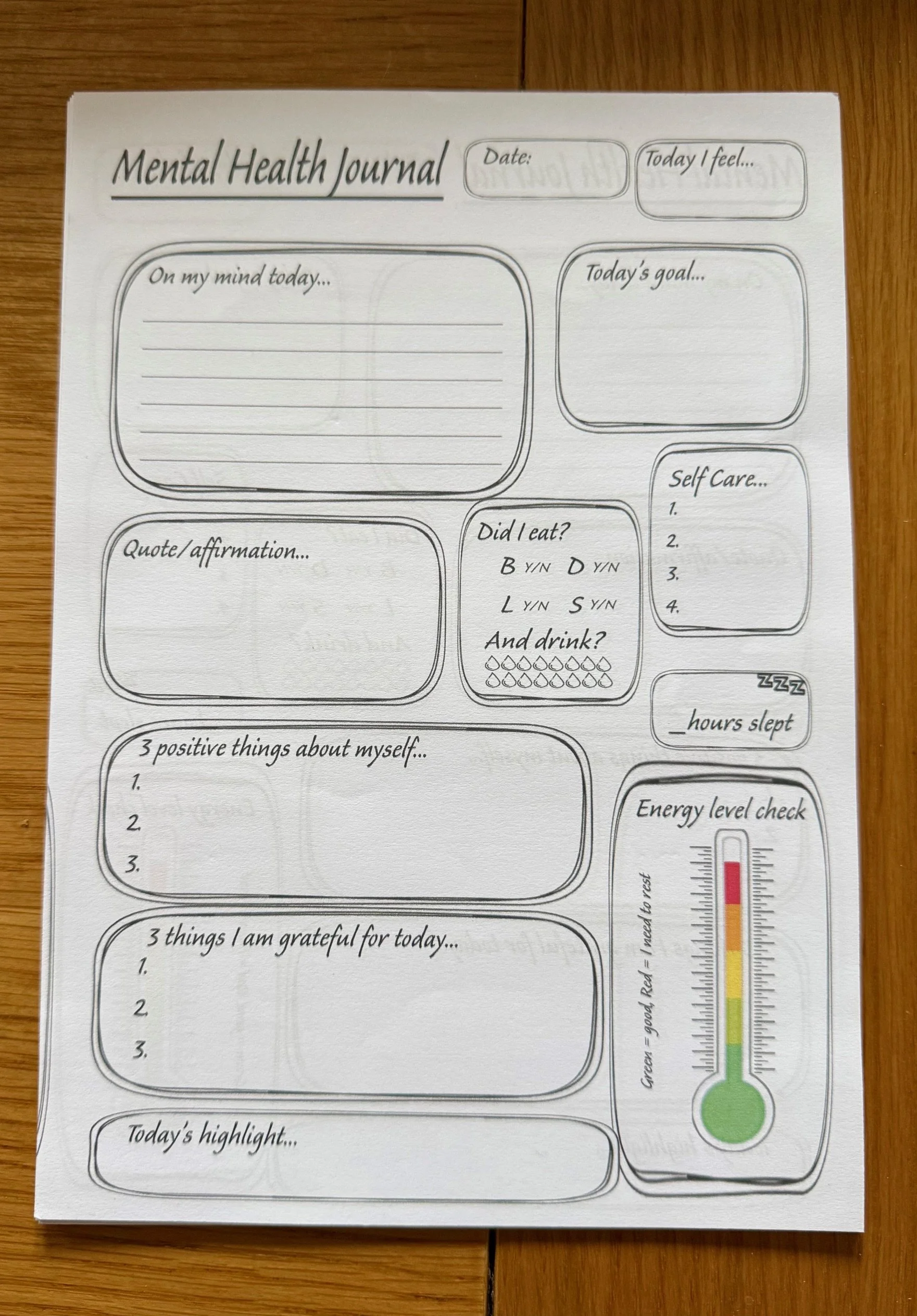 A printed mental health journal with sections for daily reflections, goals, self-care, gratitude, and positive things about oneself, along with a mood and energy level scale.
