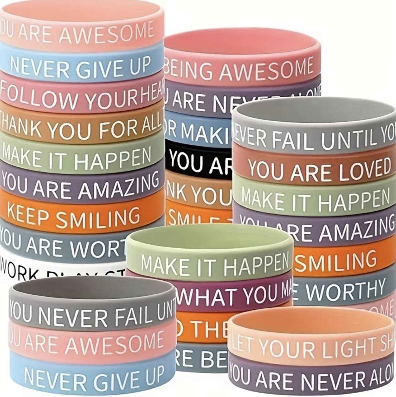 Colorful stacks of bracelets with motivational phrases including "You are awesome," "Never give up," "Follow your heart," "Thank you for all," "Make it happen," "You are amazing," "Keep smiling," "You are worthy," "Never fail until you try," "You are