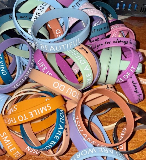A collection of colourful silicone wristbands with various motivational and positive messages, some of which include 'BEAUTIFUL,' 'LIKE A DREAM,' ' and 'YOU ARE BLESSED,' 
