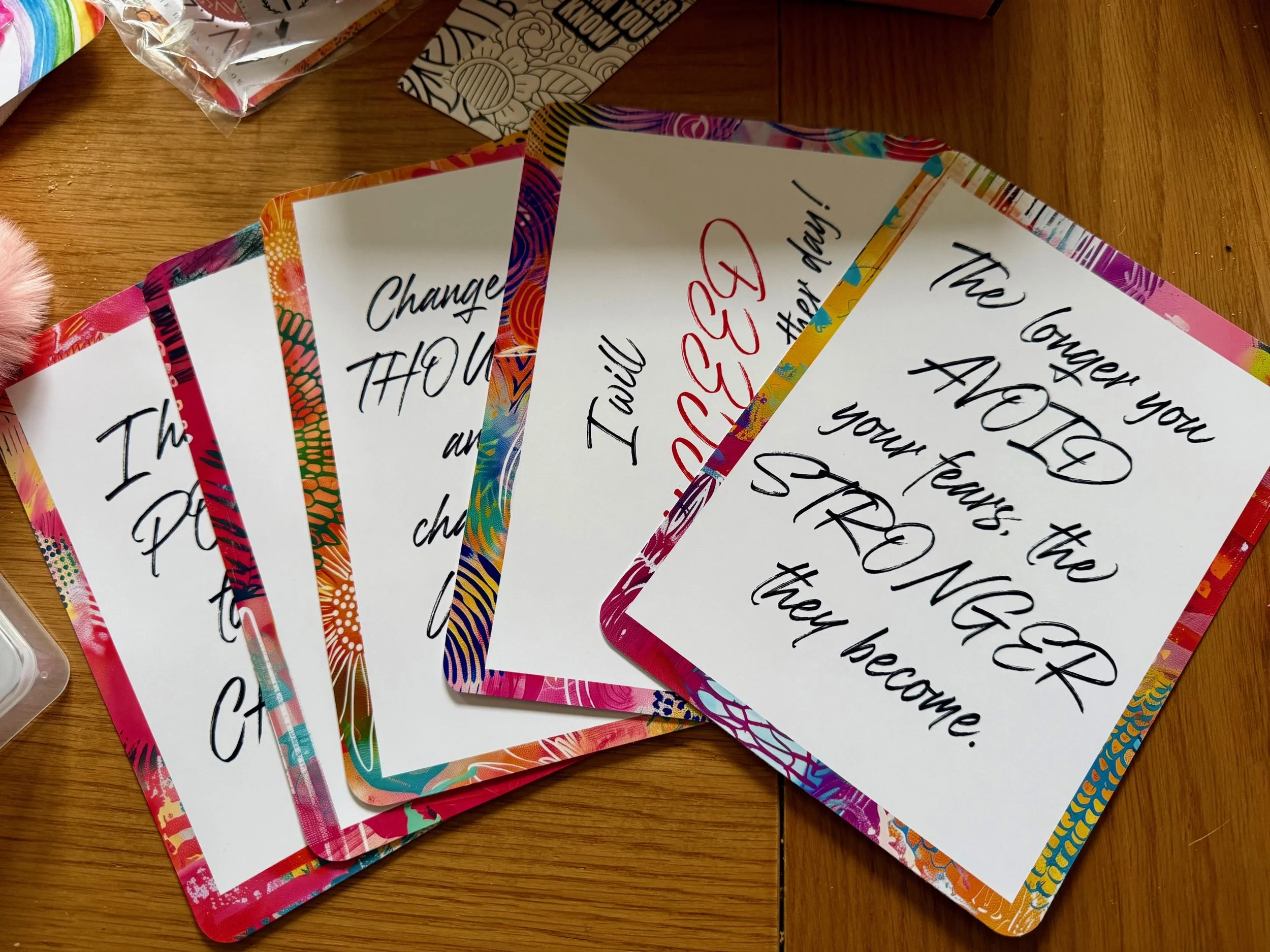 Multiple colorful cards with inspirational quotes on a wooden surface.