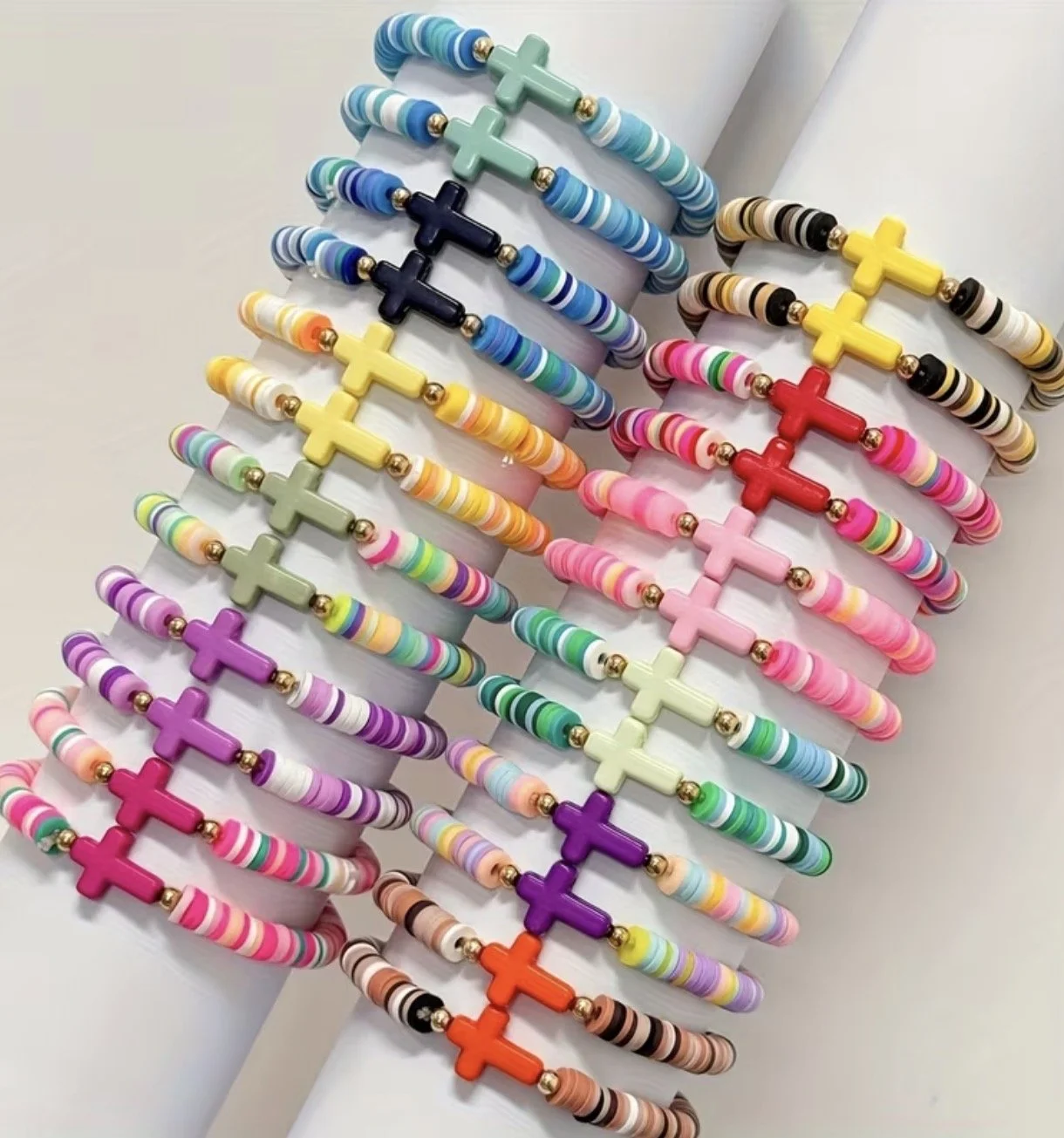 Colorful beaded bracelets with cross-shaped charms, arranged in rows on display.