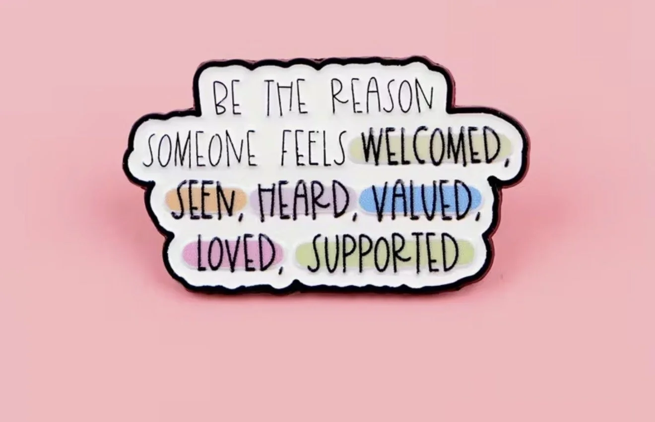 Inspirational quote pin badge that says, "Be the reason someone feels welcomed, seen, heard, valued, loved, supported" in colourful handwritten letters. Mental Health (Anchored Thoughts)