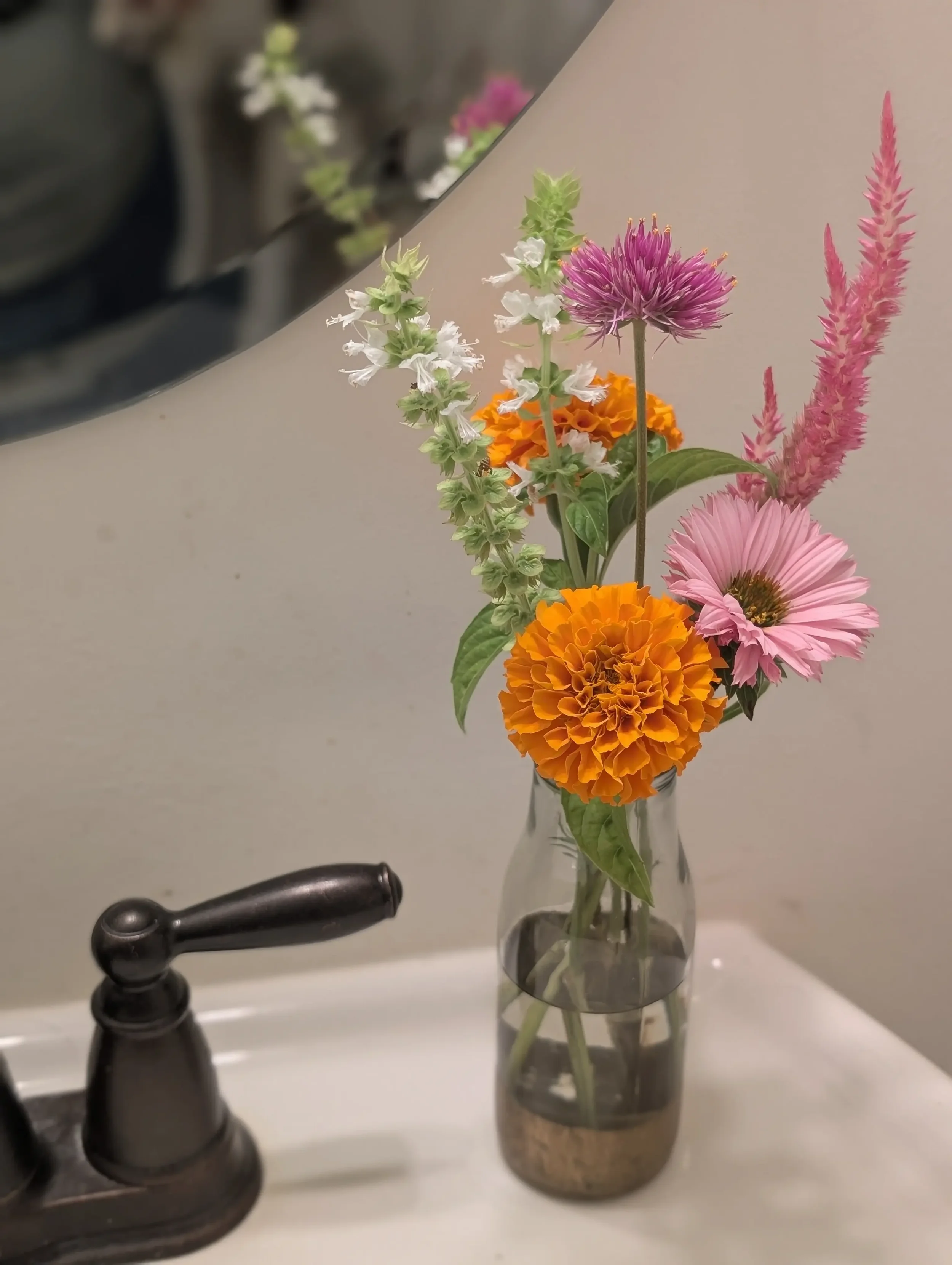 Extra DIY wedding flowers styled in a small glass bud vase with seasonal blooms for a venue restroom