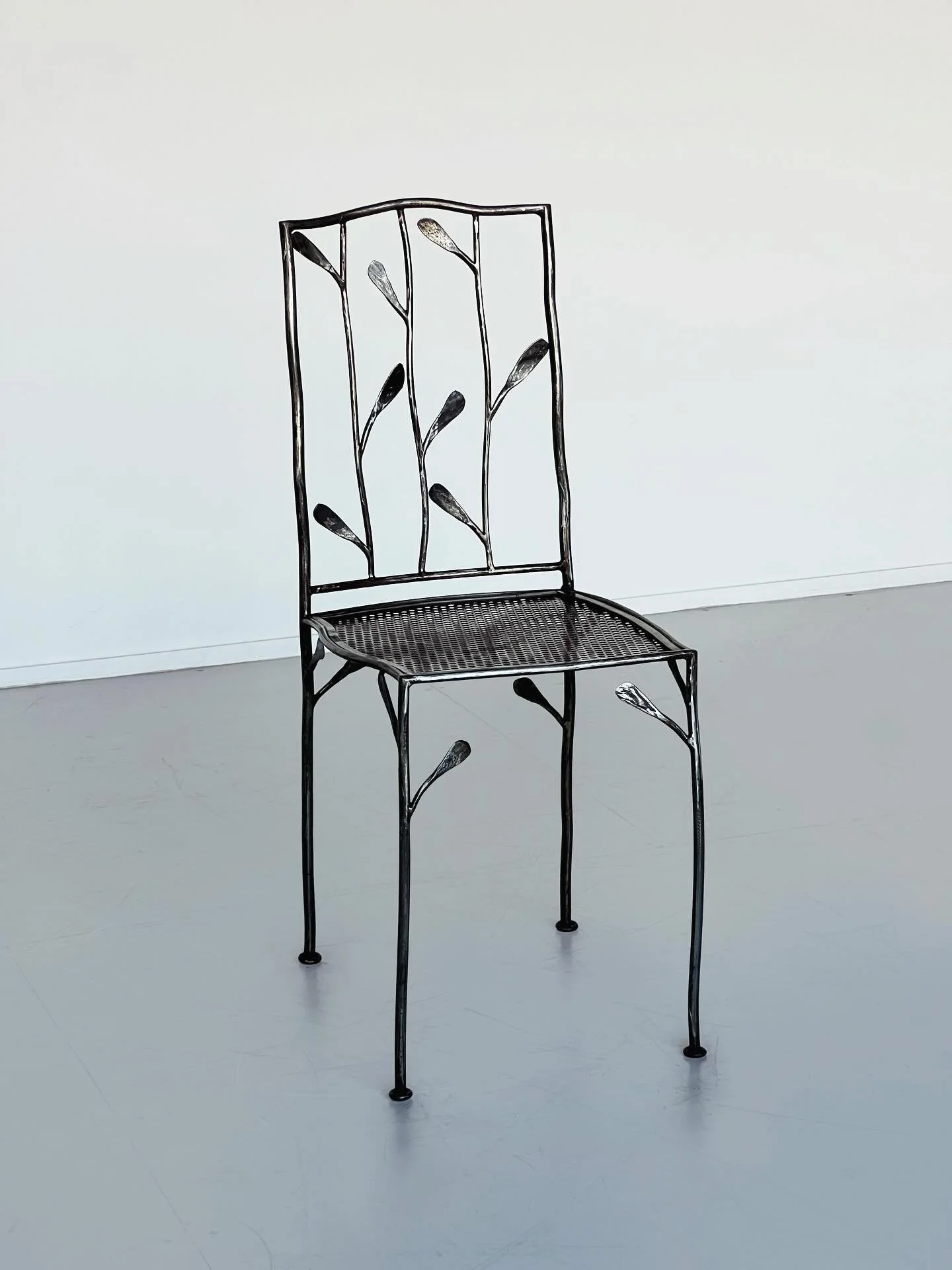 New: A sculptural chair crafted in steel,  balances strength with detail. The structure is adorned with sculptural leaves, each shaped in metal to create a natural rhythm across the frame. Both decorative and functional, it carries the weight and pre
