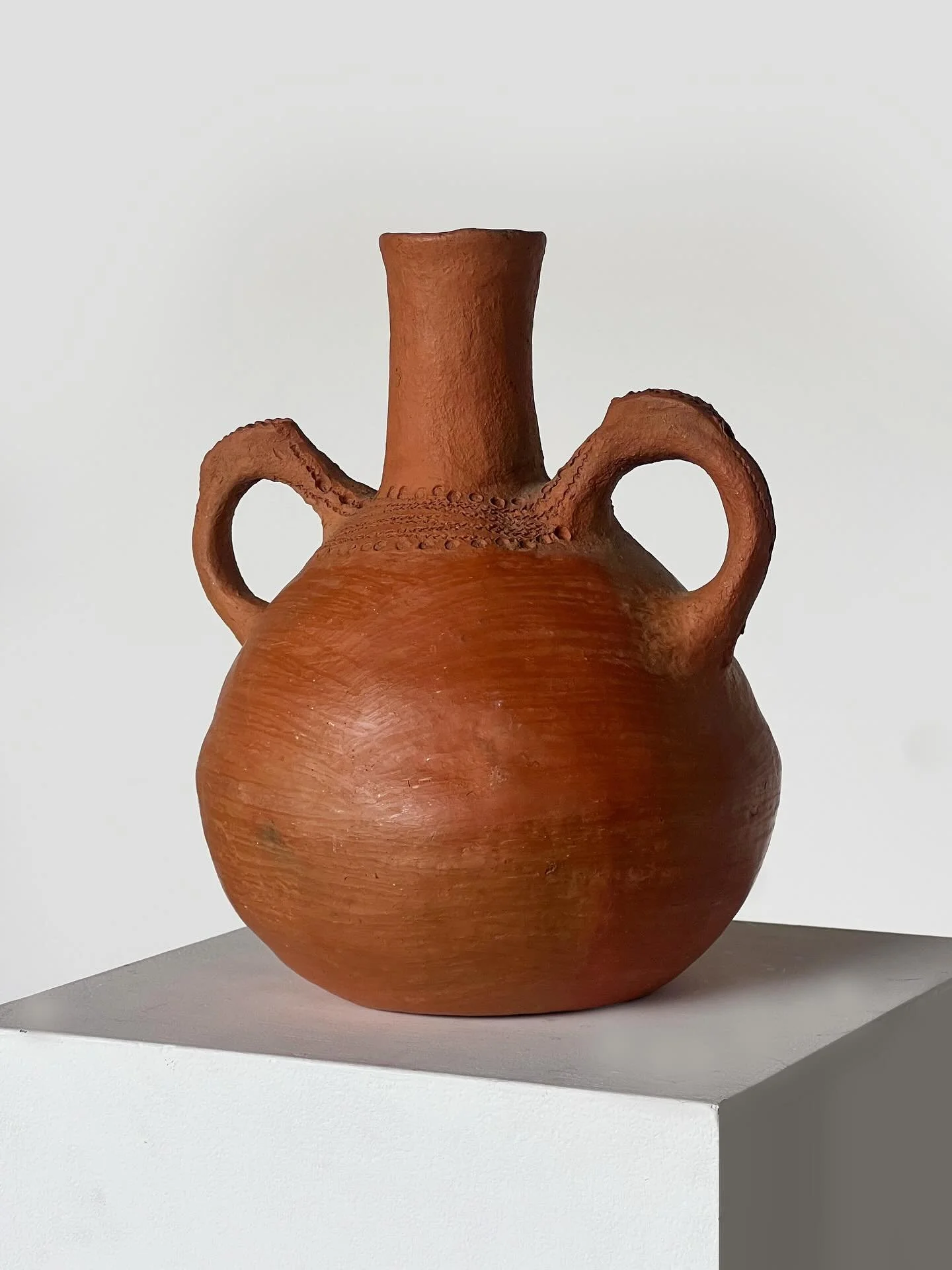 New: Crafted by hand, this sculptural terracotta vase brings a modern sensibility to an ancient form. Its rounded silhouette, elongated neck, and bold twin handles evoke the tactility and elegance of Mediterranean pottery, subtle surface markings rev