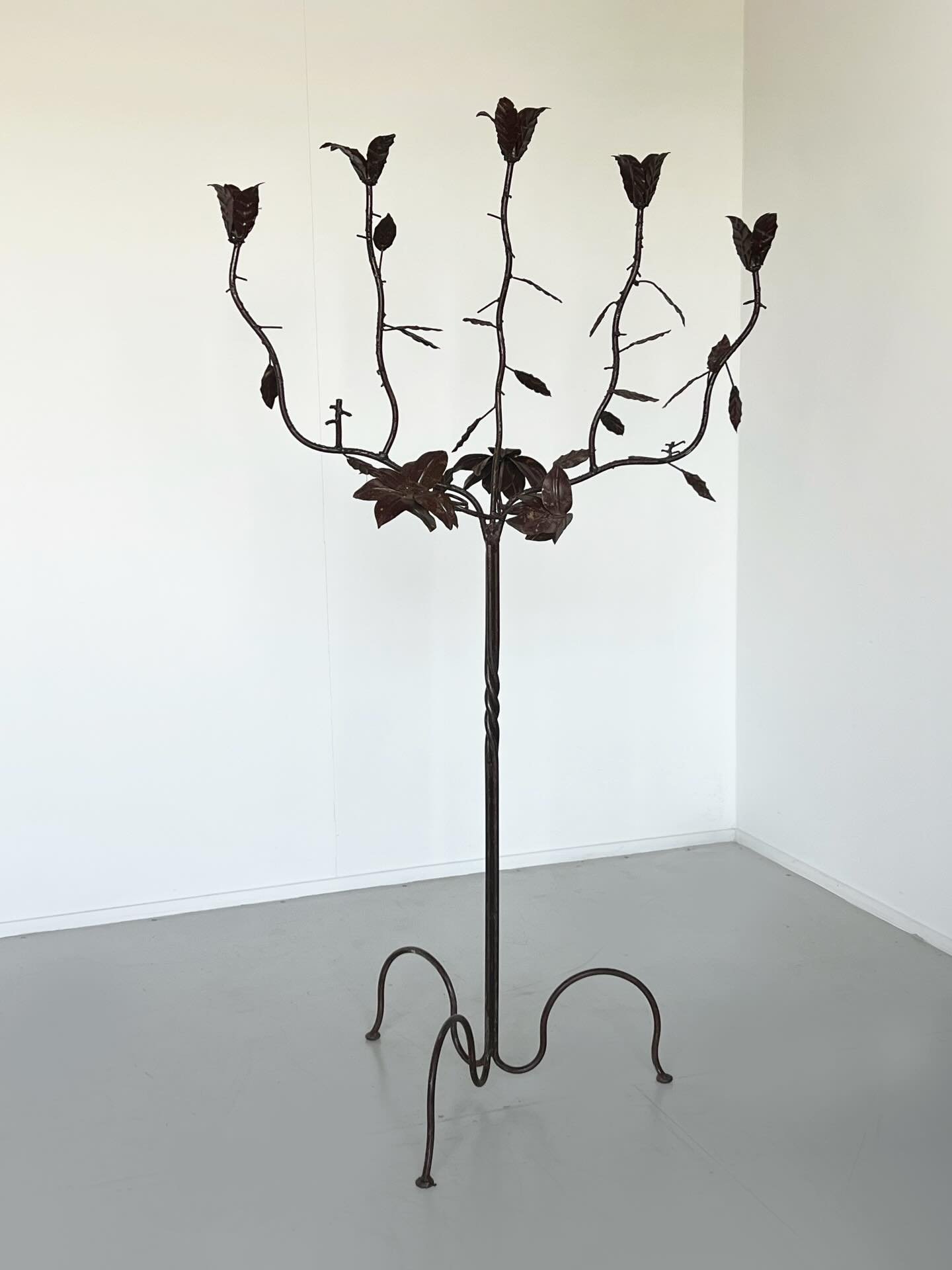A sculptural bronzed candelabra with branching, vine-like arms, delicate hand-forged leaves and floral details give the piece an organic, almost botanical silhouette. Its dark, aged finish and graceful, organic form create a striking, timeless presen