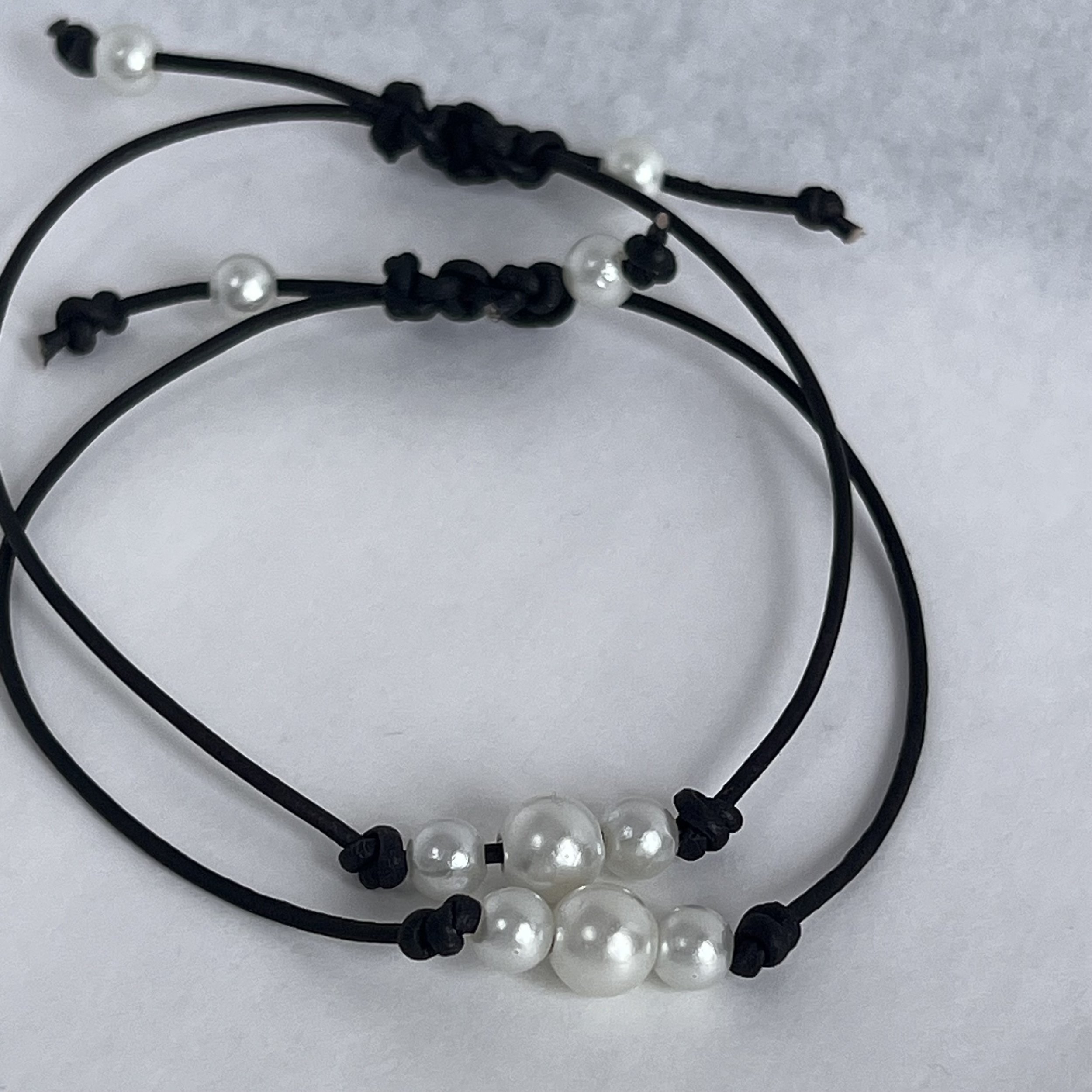 Minimalist handmade bracelet with pearl-style bead on black leather cord.