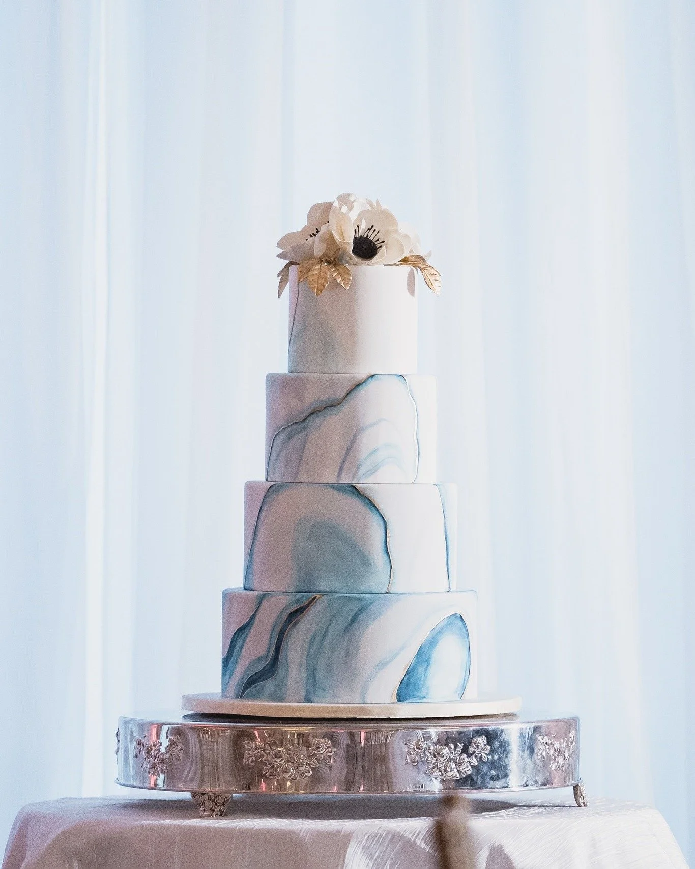 When the cake becomes part of the d&eacute;cor. 

This marbled beauty understood the assignment. The soft blue detailing tied effortlessly into the florals and reception design, creating one cohesive look from the tablescape to the sweetest detail of