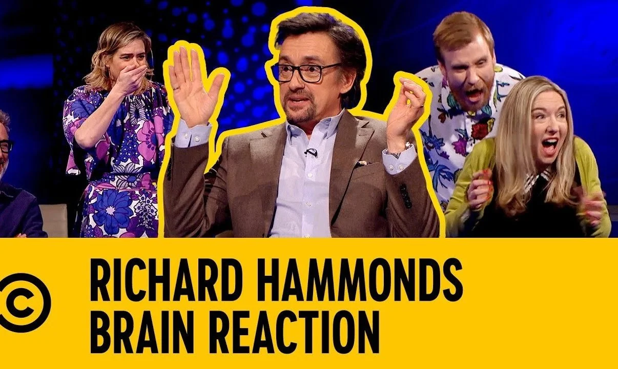 A man in a suit raises his hands surrounded by three other people reacting emotionally. The image has text reading "Richard Hammond's Brain Reaction." The background is brightly colored with a blue and purple gradient.