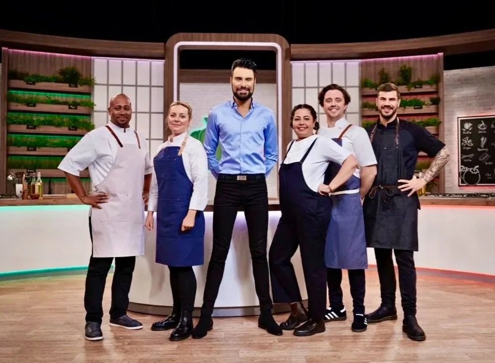 Group of chefs and host posing in a colorful kitchen set