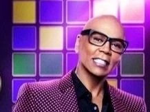 Person wearing glasses and a polka dot jacket in front of colorful squares background.