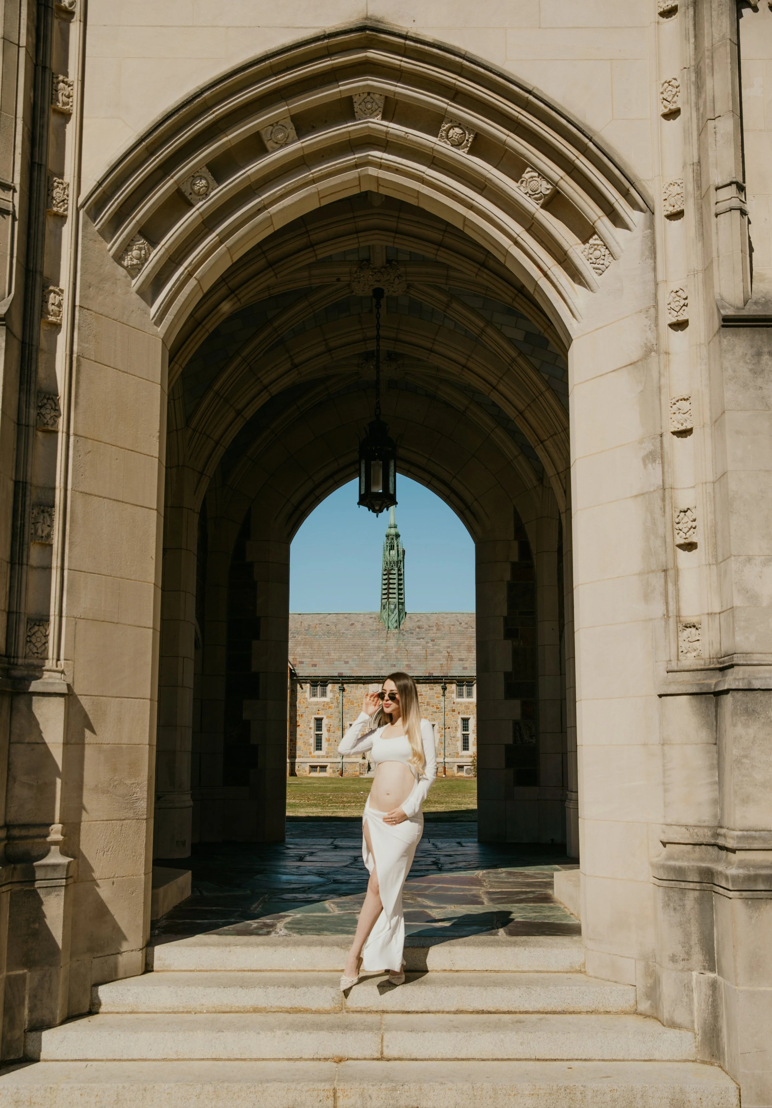 Woman walking under gothic archway at historic university campus