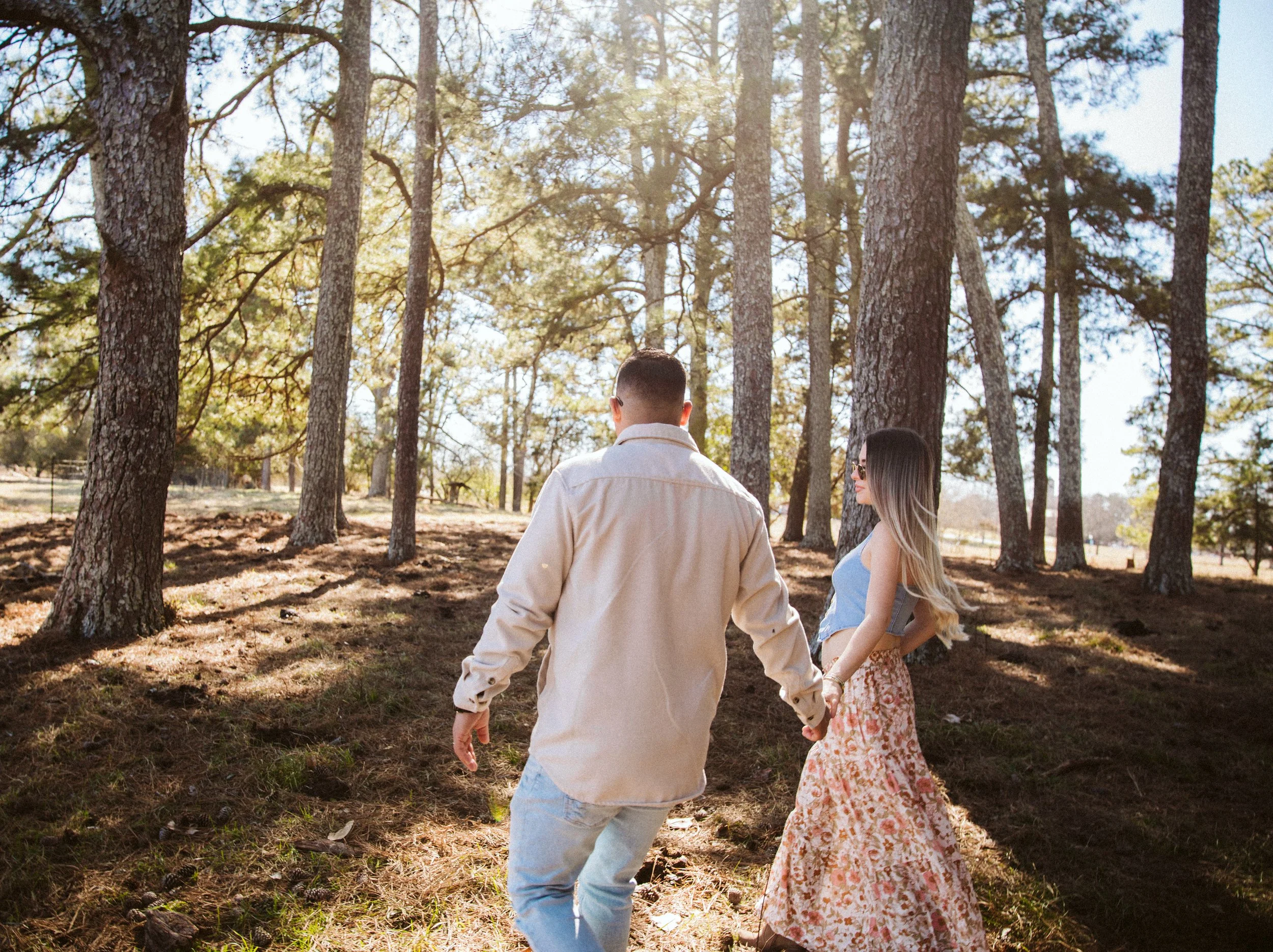 Couple walking together through sunlit pine forest