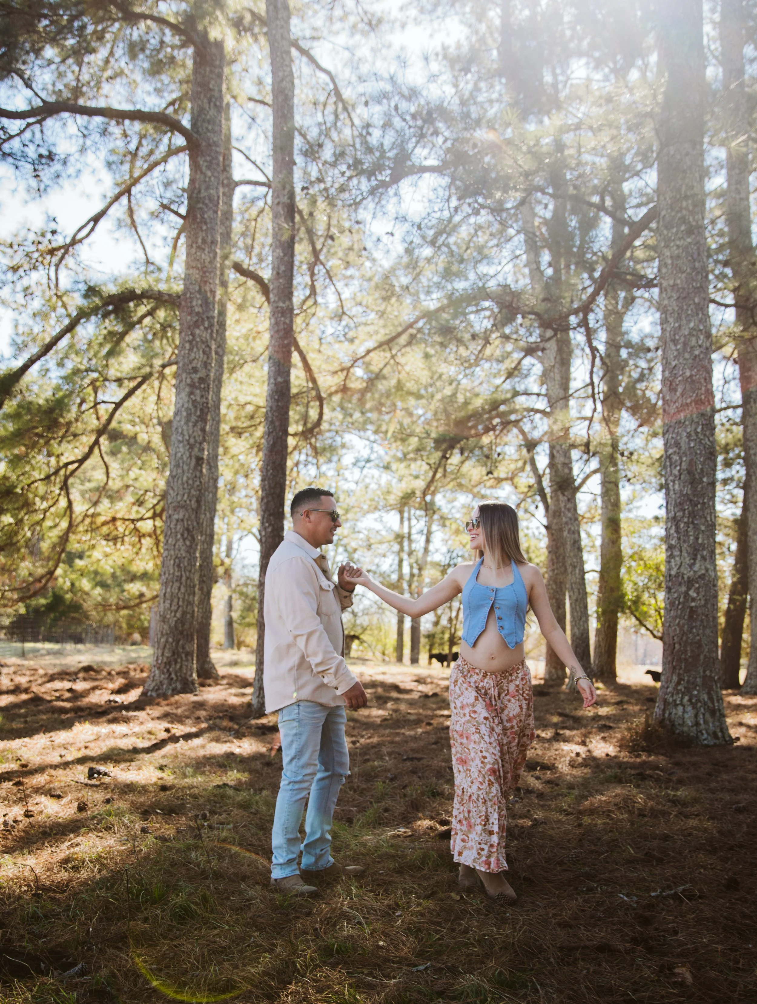 Couple holding hands during outdoor maternity session in pine forest