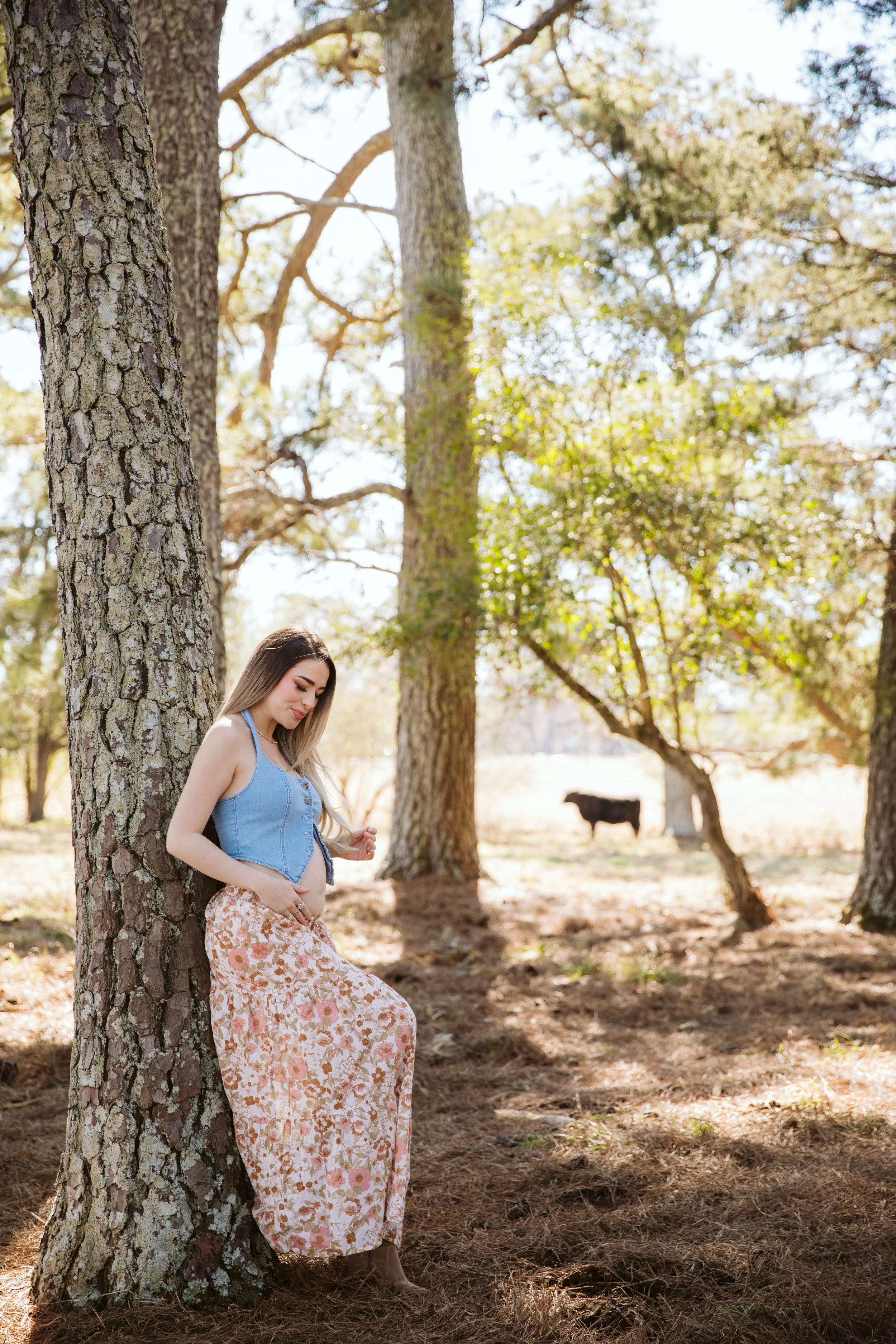 Pregnant woman leaning against tree in natural outdoor maternity session