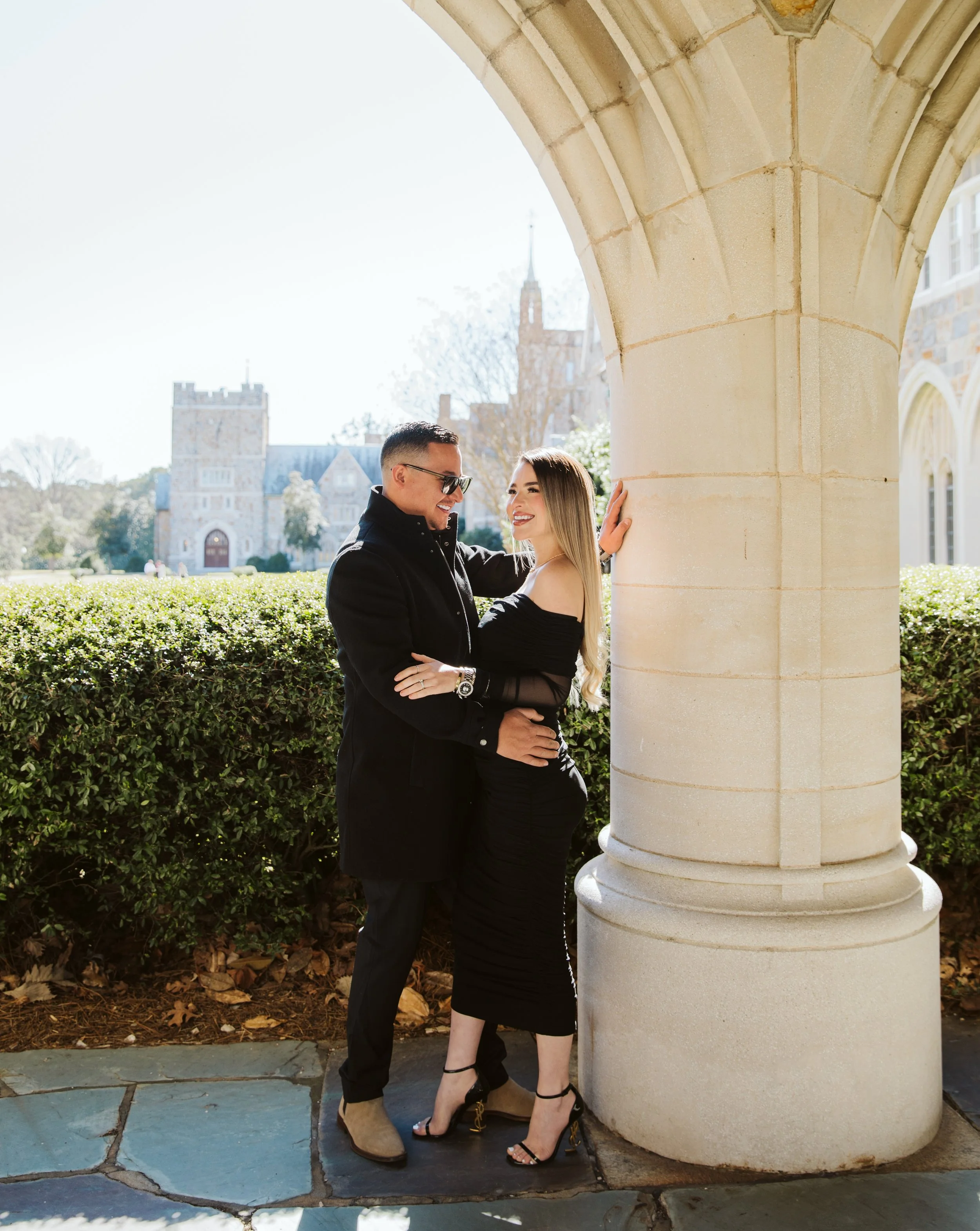 Elegant couple embracing under stone archway at historic campus
