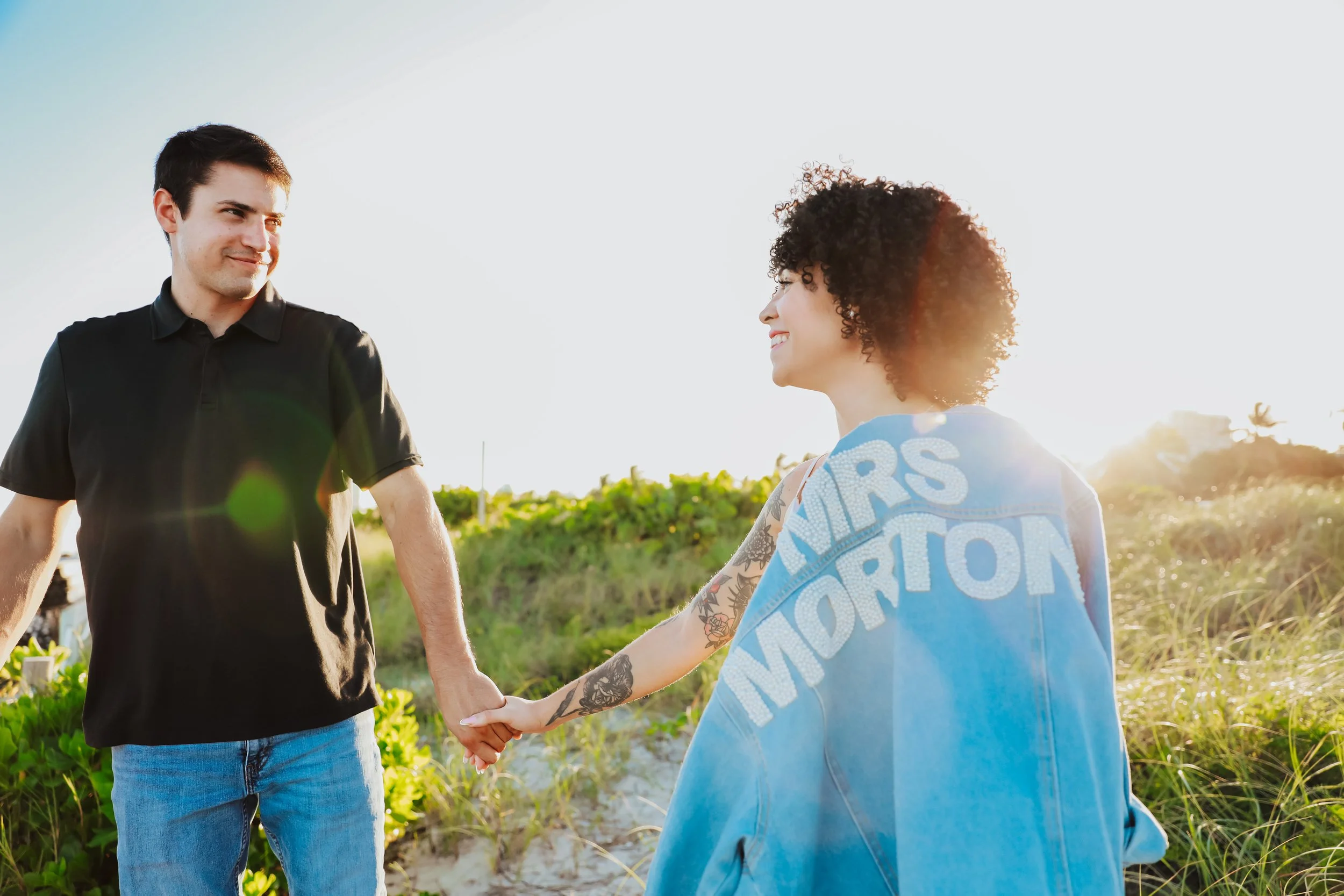 Couple holding hands during beachside engagement session