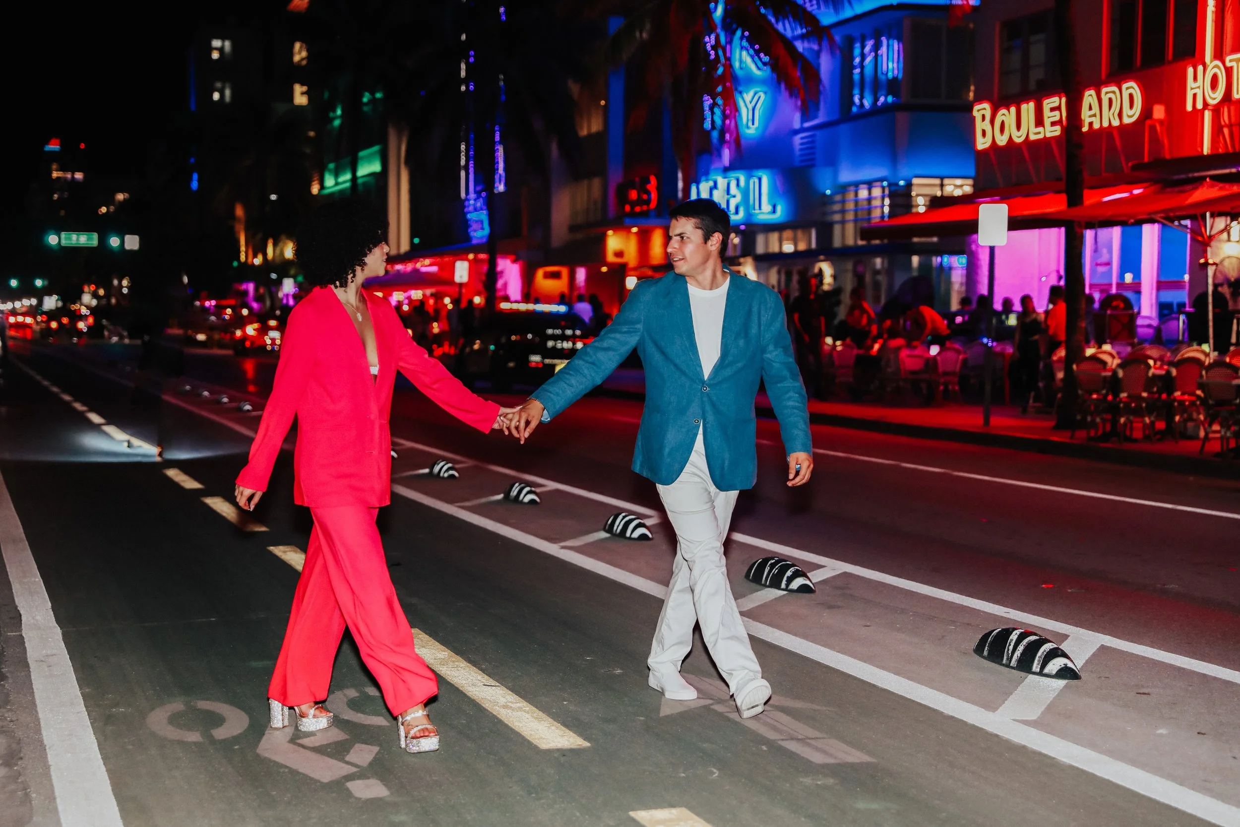 Couple walking through neon-lit street at night