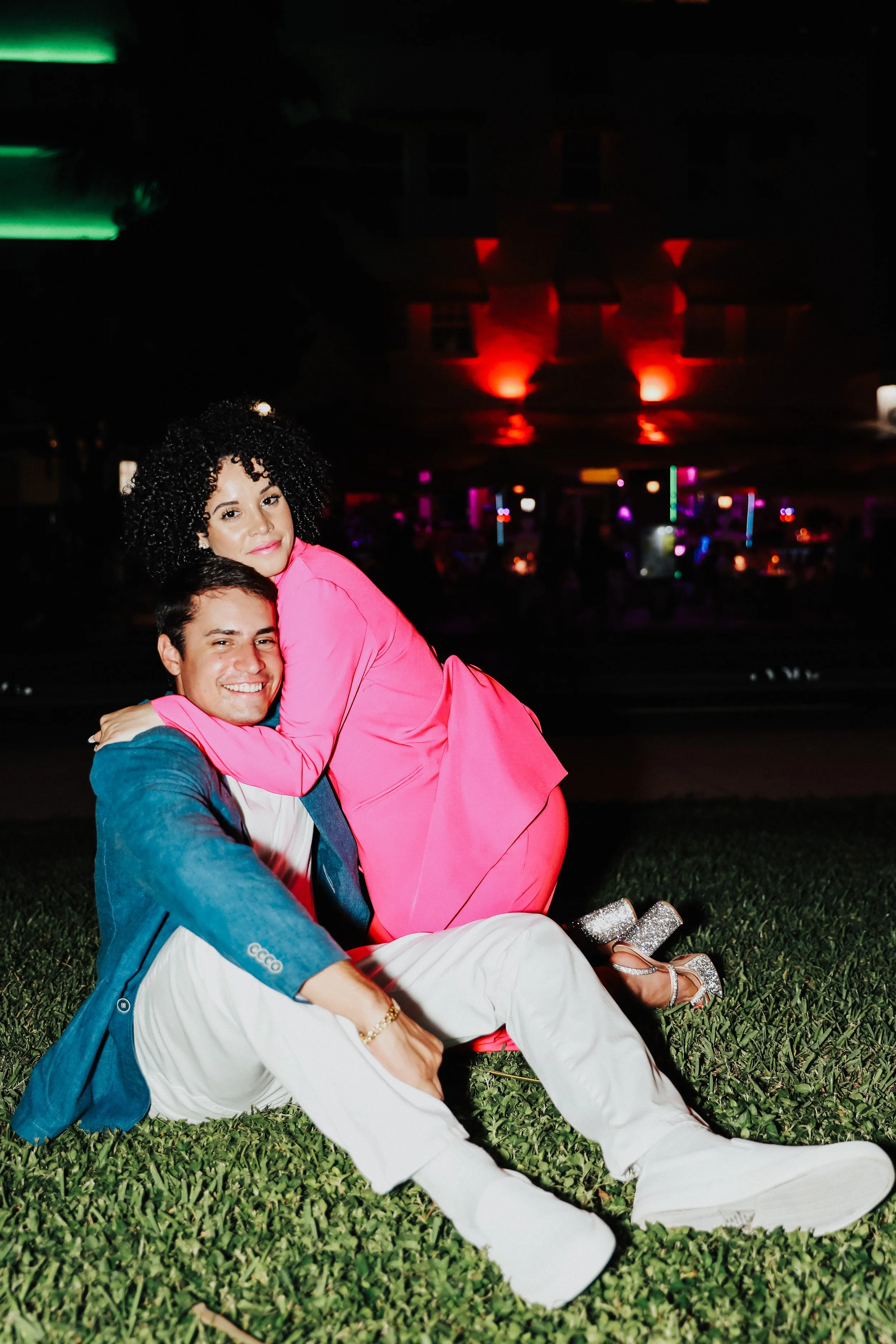 Playful engagement photo with couple sitting on grass