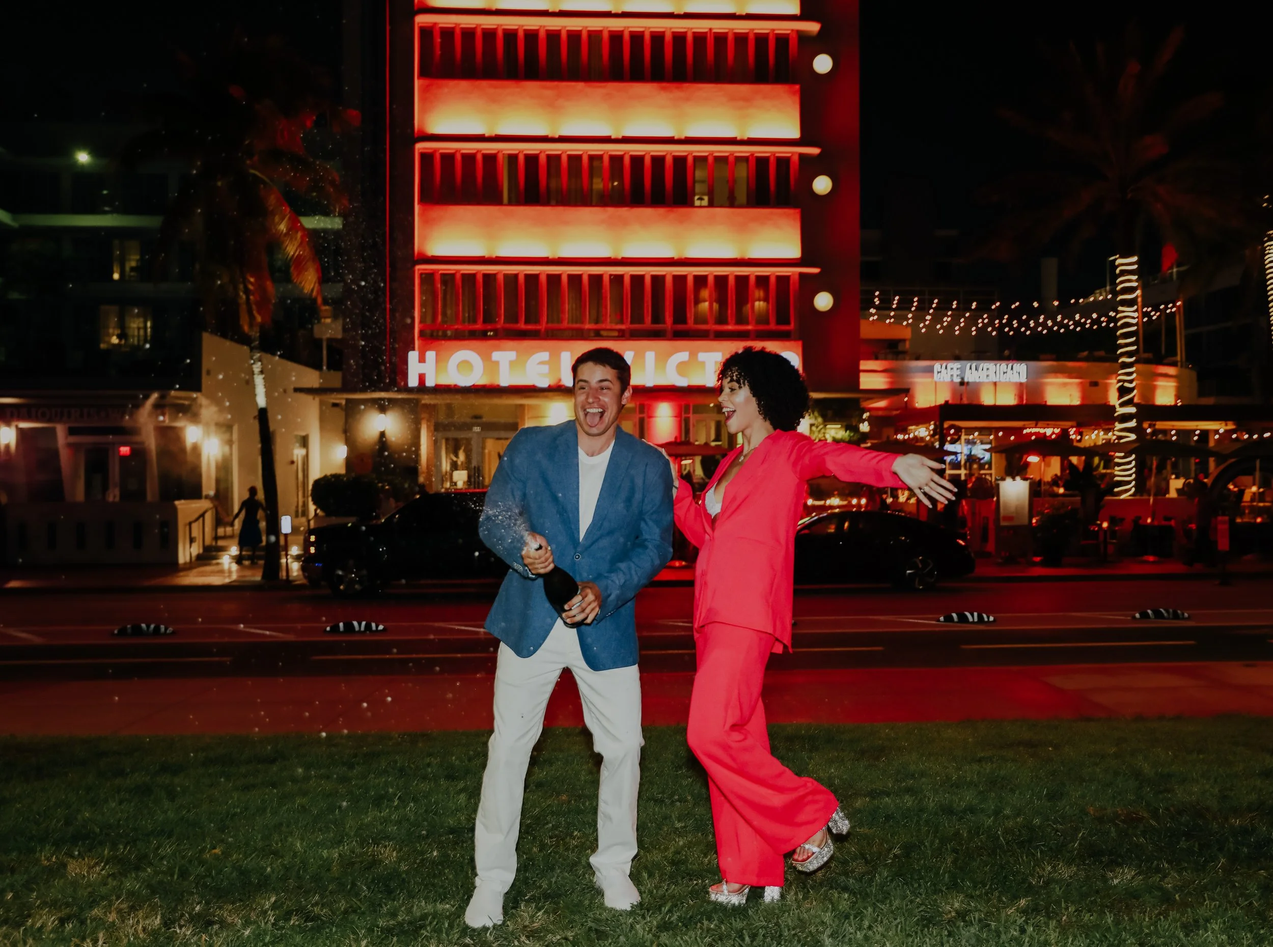 Engagement photo with neon hotel lights in background