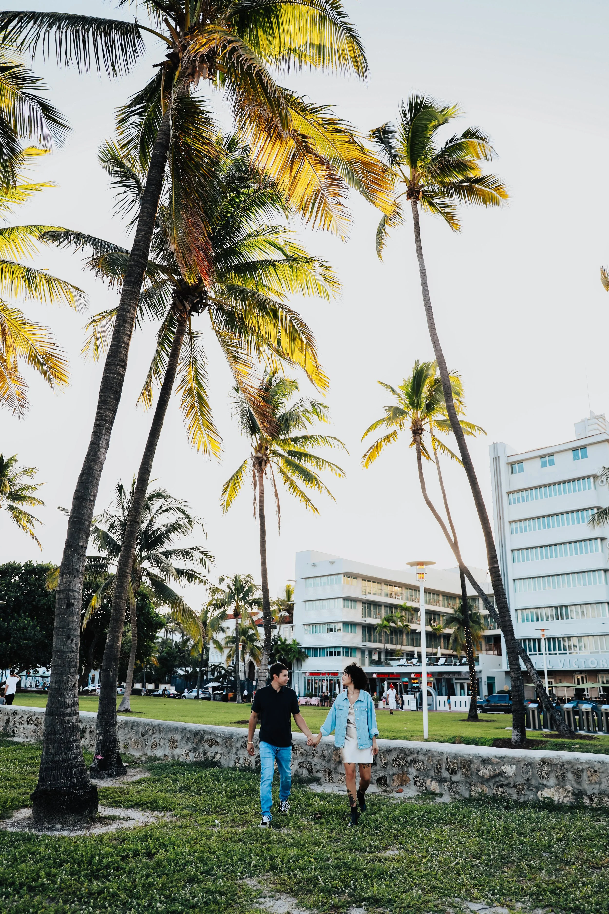 Couple walking near palm trees and city buildings