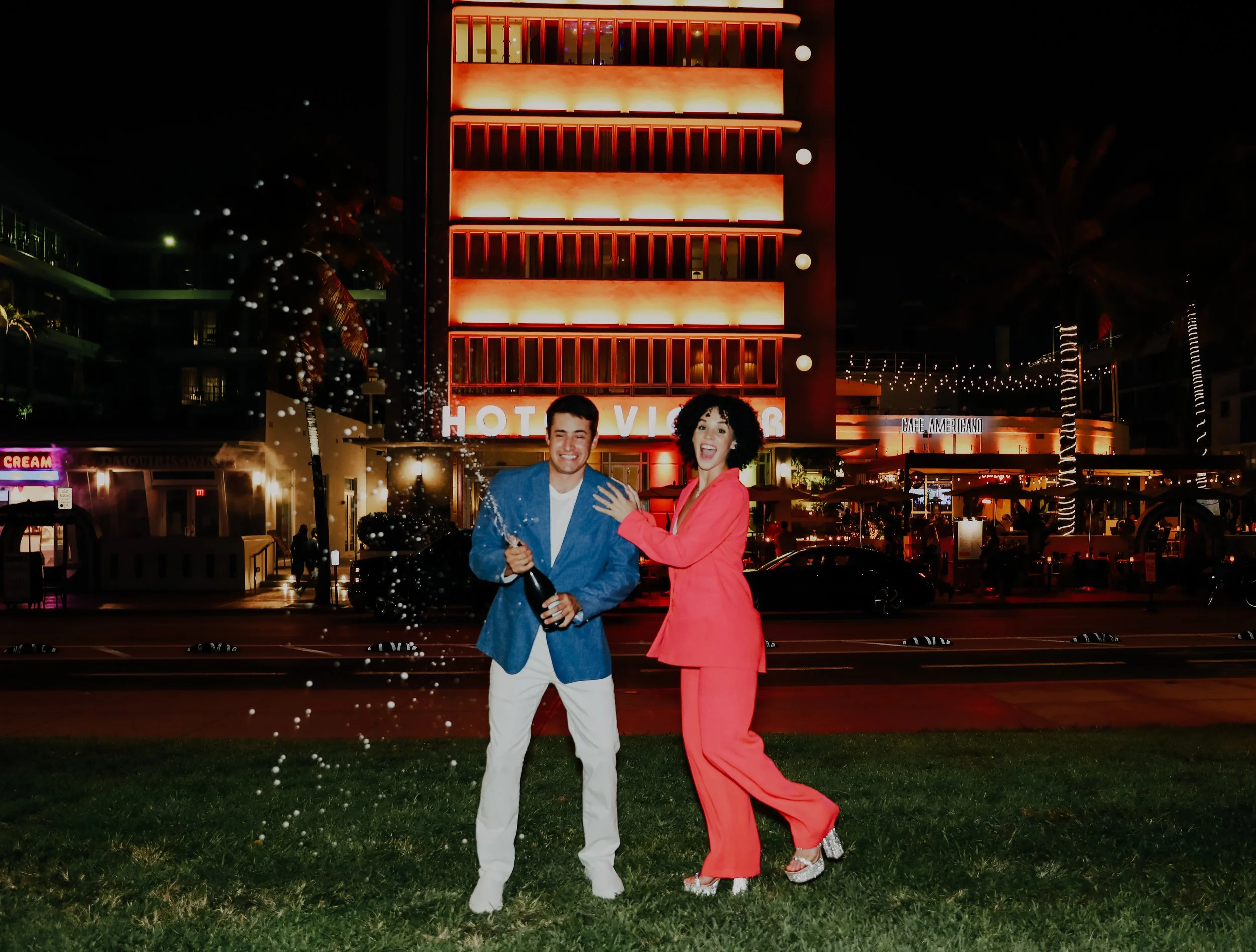 Couple posing in front of lit hotel at night