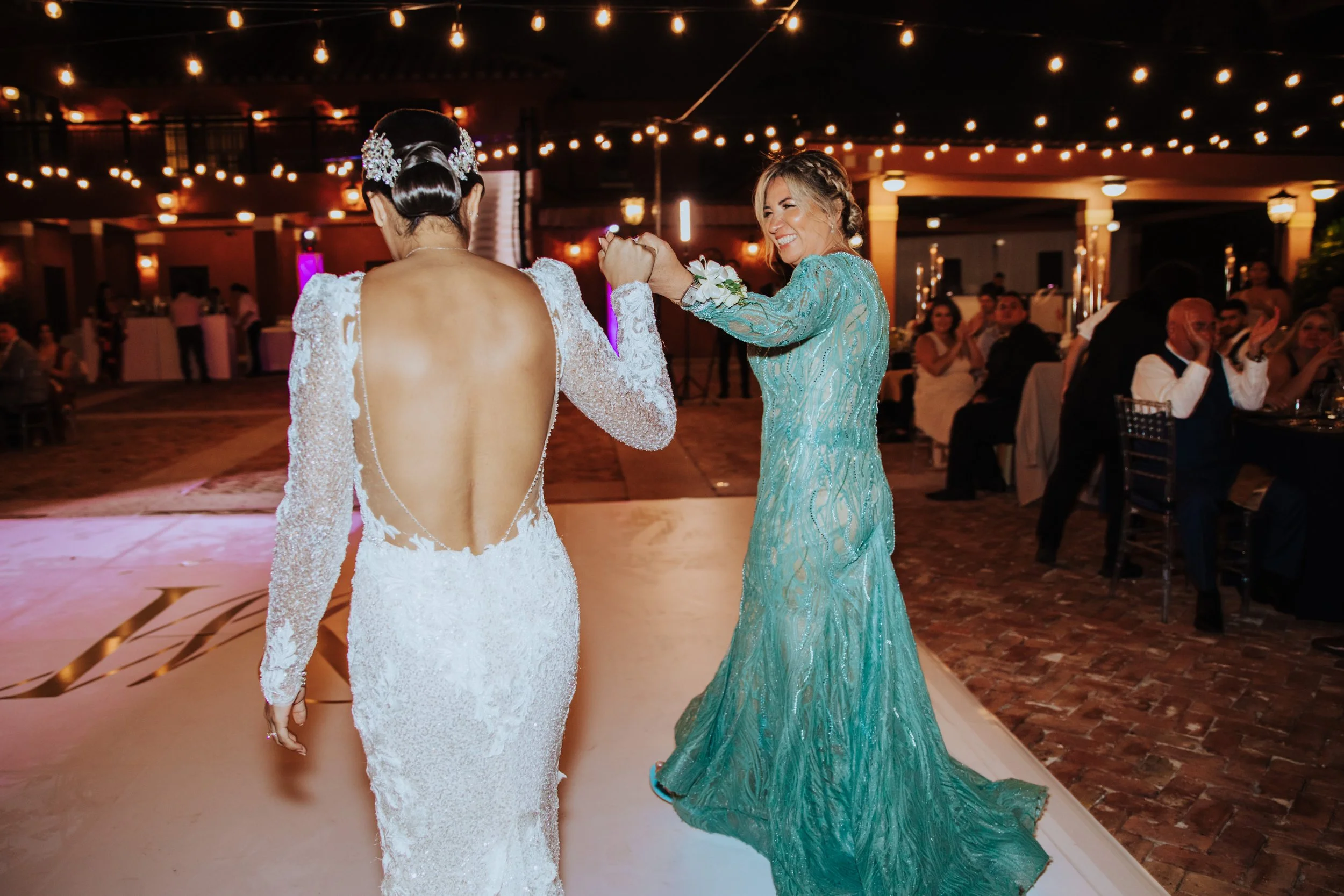 Bride and guests dancing in formal dresses at night