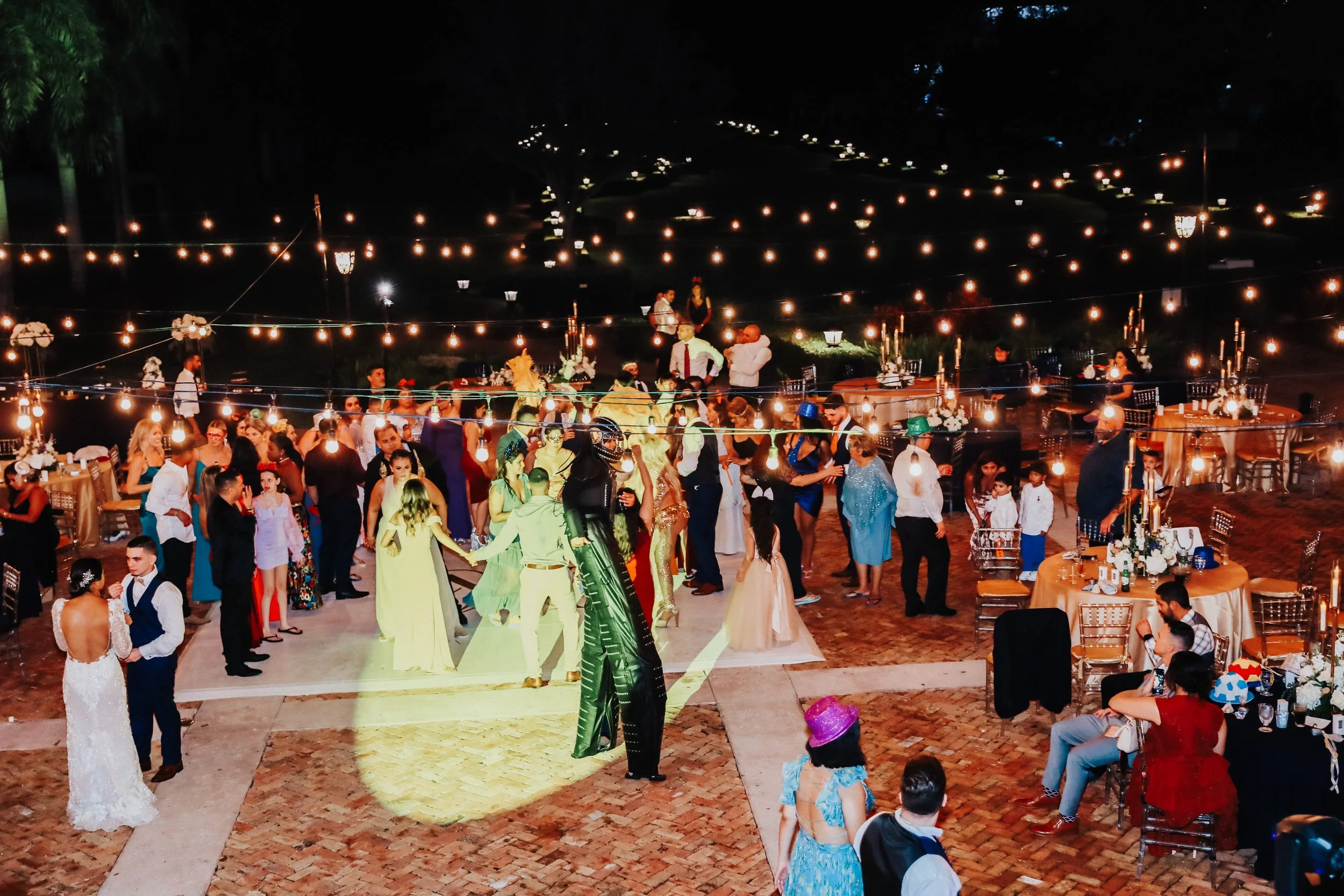 Outdoor wedding reception with large crowd dancing