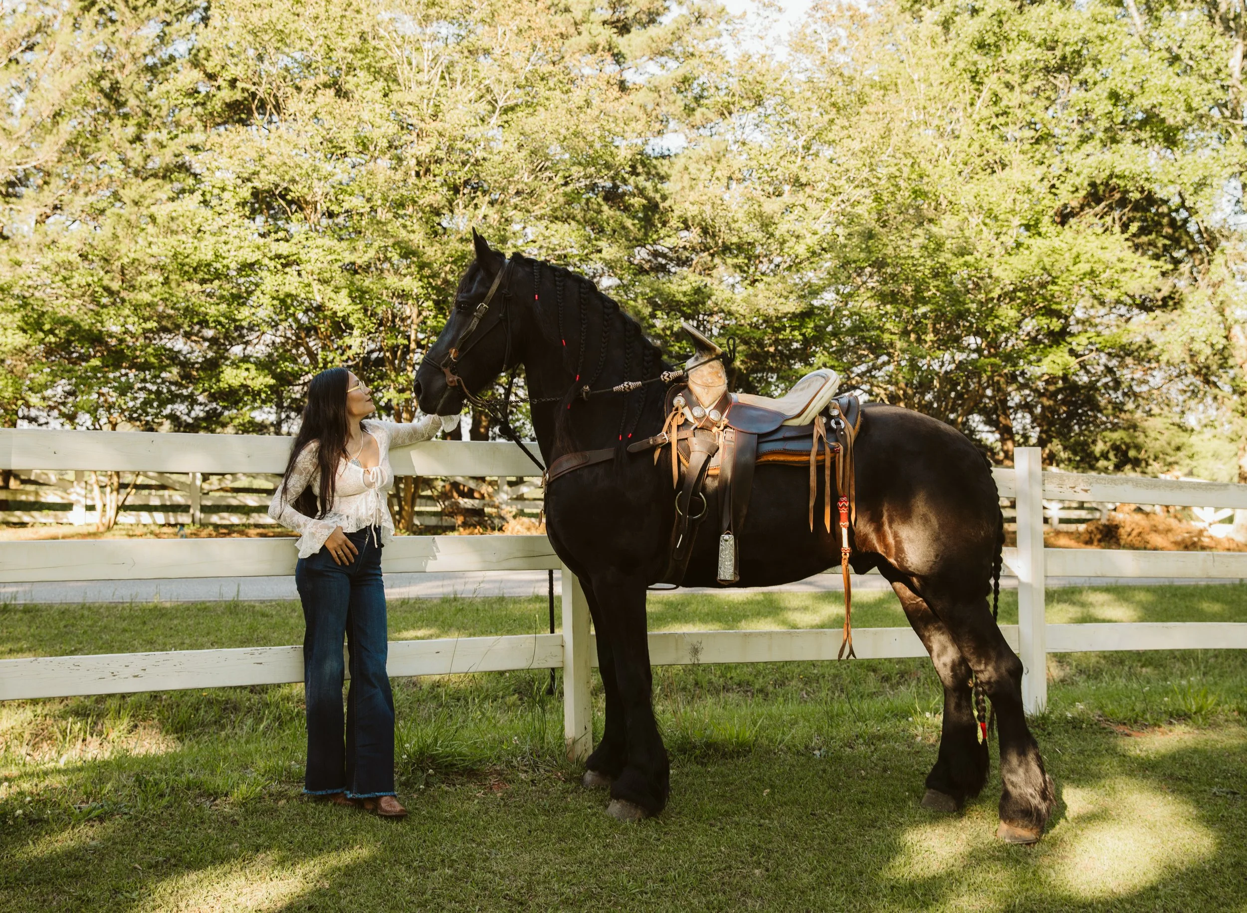 Woman standing beside Friesian horse outdoors